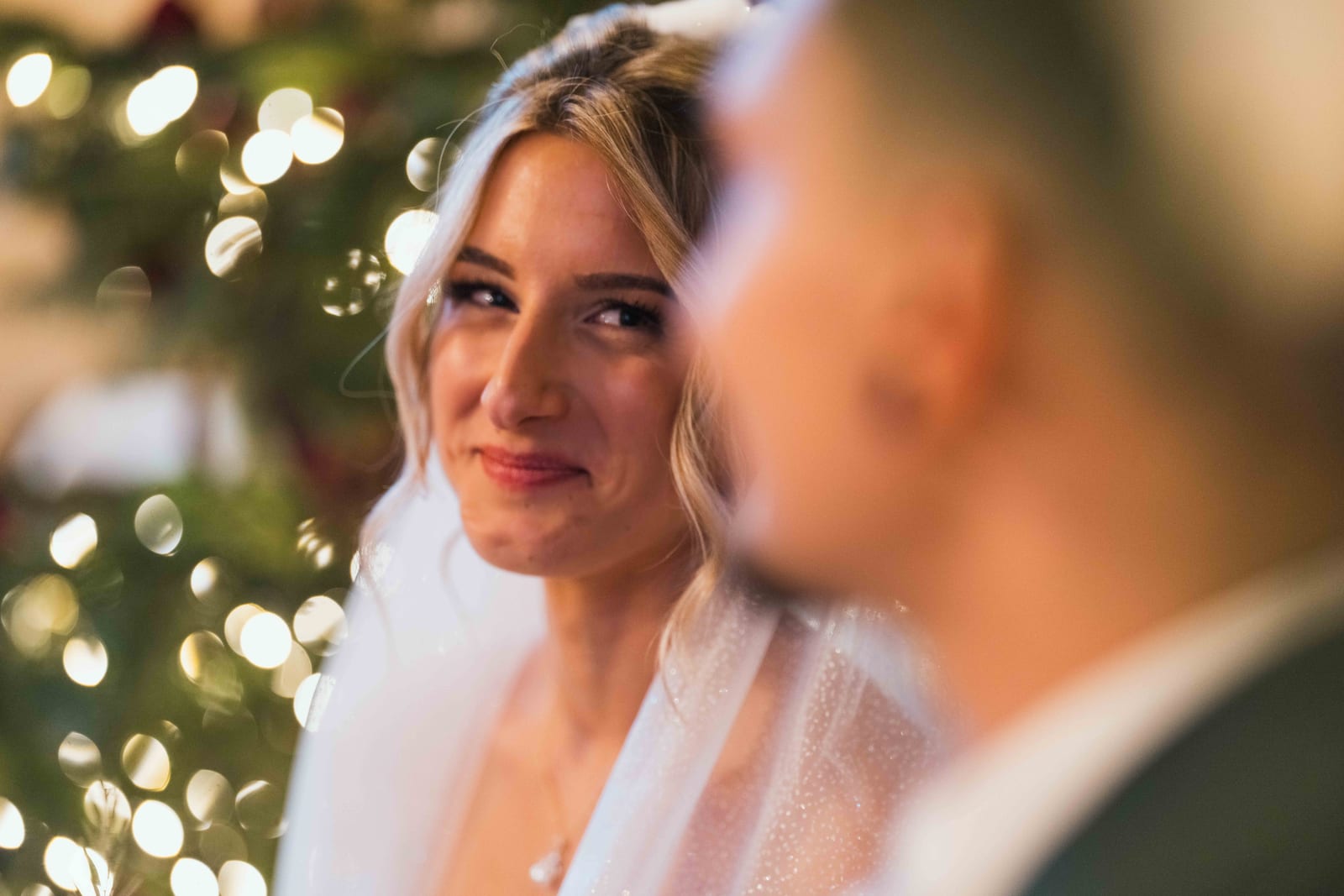 Alice souriante devant le sapin de Noël illuminé, guirlandes dorées en bokeh, mariage au Château de Pontarmé, par Jean-Baptiste Argyre (Jaysphotography)
