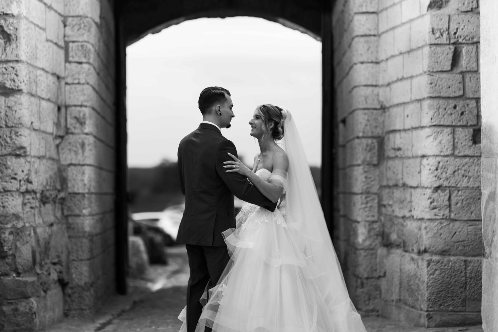Couple en contre-jour sous une arche de pierre ancienne, noir et blanc, mariage au Château de Pontarmé, par Jean-Baptiste Argyre (Jaysphotography)