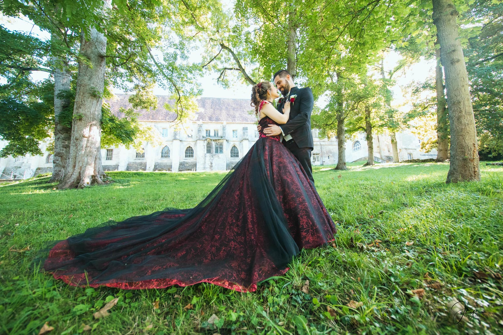 Amandine seule dans le parc de l'abbaye, robe bordeaux à longue traîne sur l'herbe verte, mariage au Abbaye Royale du Moncel, par Jean-Baptiste Argyre (Jaysphotography)