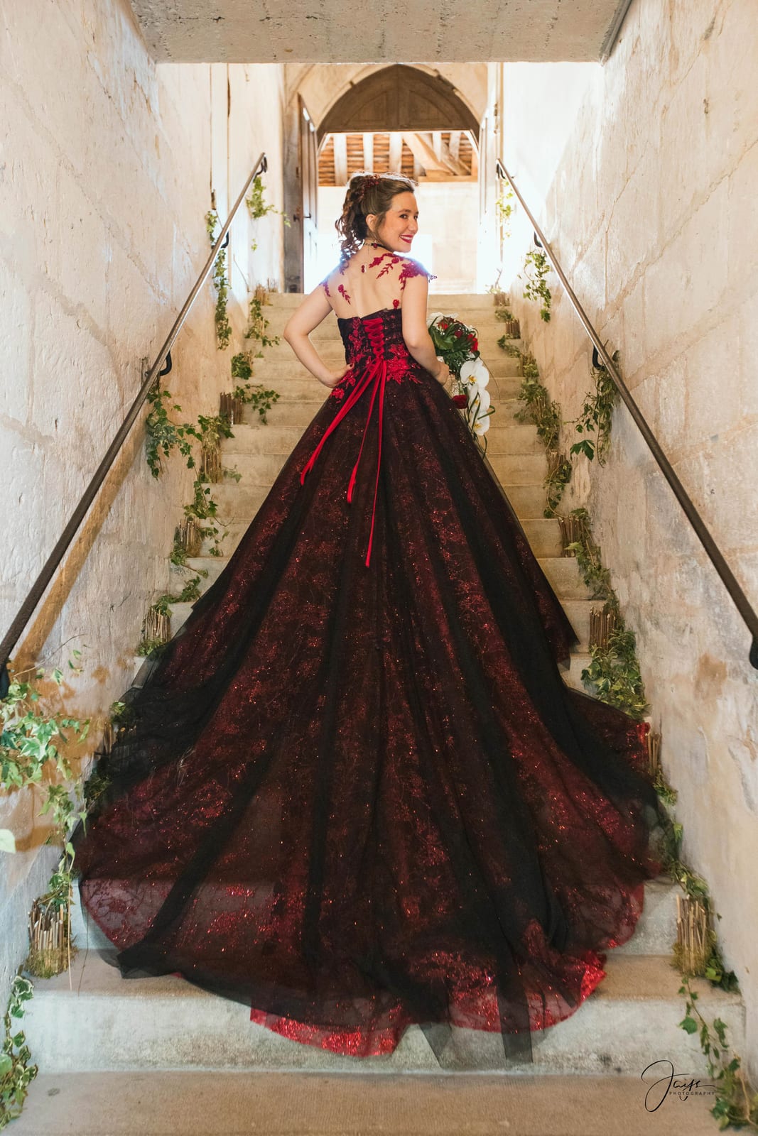 Amandine sur l'escalier de pierre de l'Abbaye du Moncel, robe bordeaux et noire à traîne, mariage au Abbaye Royale du Moncel, par Jean-Baptiste Argyre (Jaysphotography)