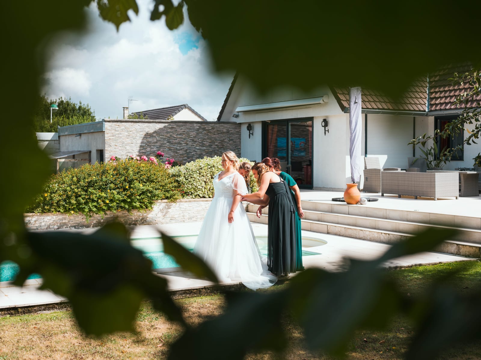 Anne-Sophie et Issa devant la façade du Domaine du Mont Rouge, robe blanche et costume sombre, ciel d'été dégagé, mariage au Domaine du Mont Rouge, par Jean-Baptiste Argyre (Jaysphotography)