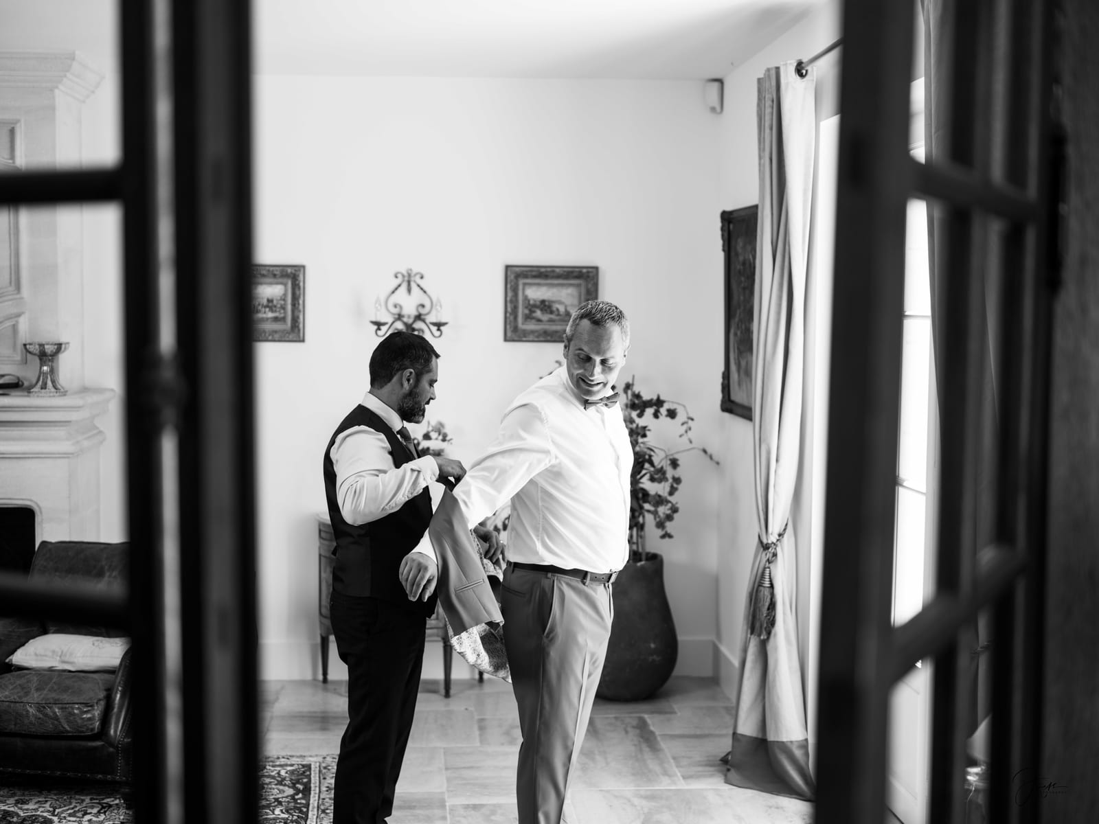 Vincent de dos dans un couloir baigné de lumière naturelle, attendant la cérémonie, mariage au Domaine de la Fauconnie, par Jean-Baptiste Argyre (Jaysphotography)