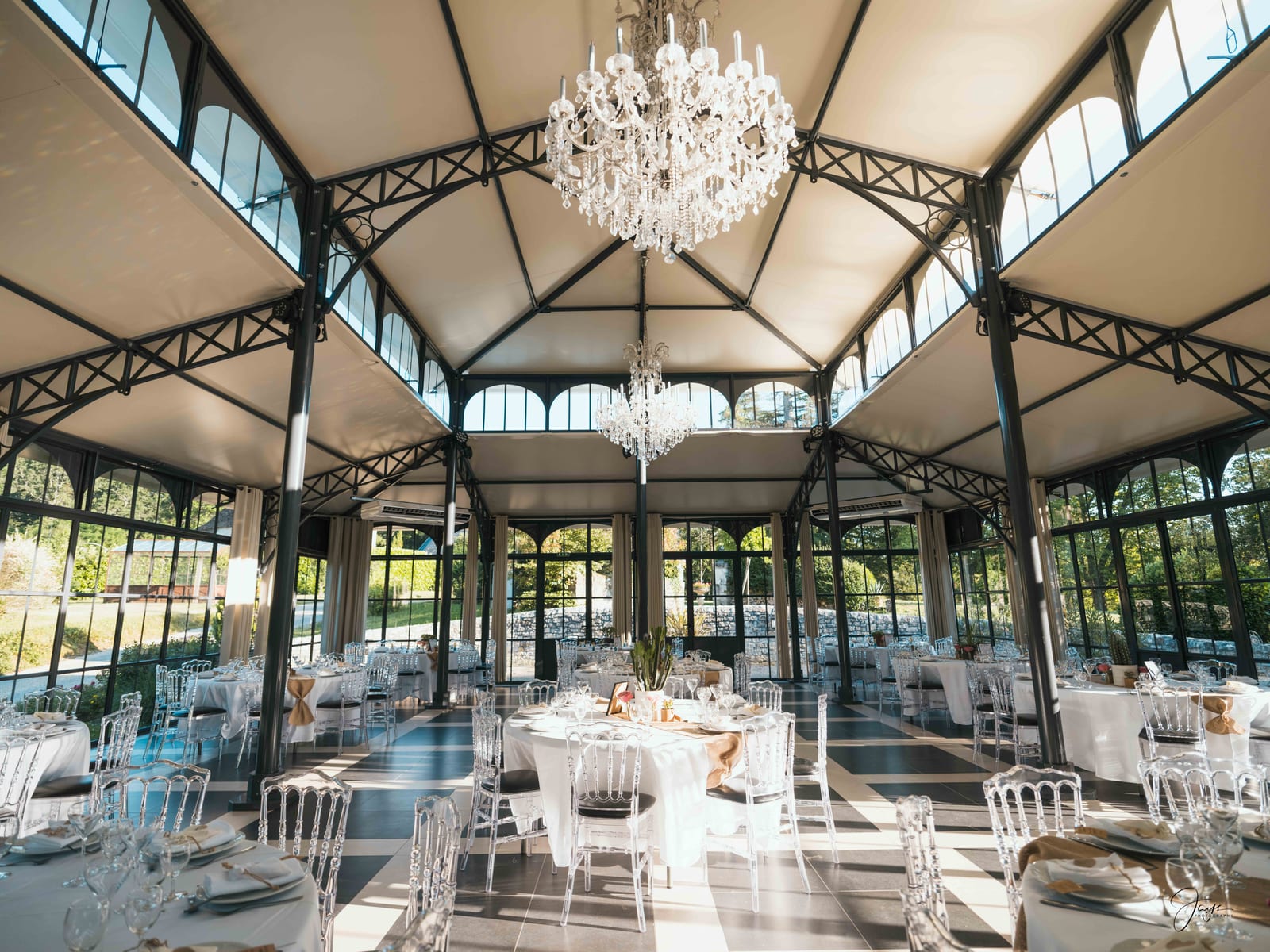 Salle de réception sous verrière dressée pour le dîner, lumière naturelle zénithale, mariage au Domaine de la Fauconnie, par Jean-Baptiste Argyre (Jaysphotography)