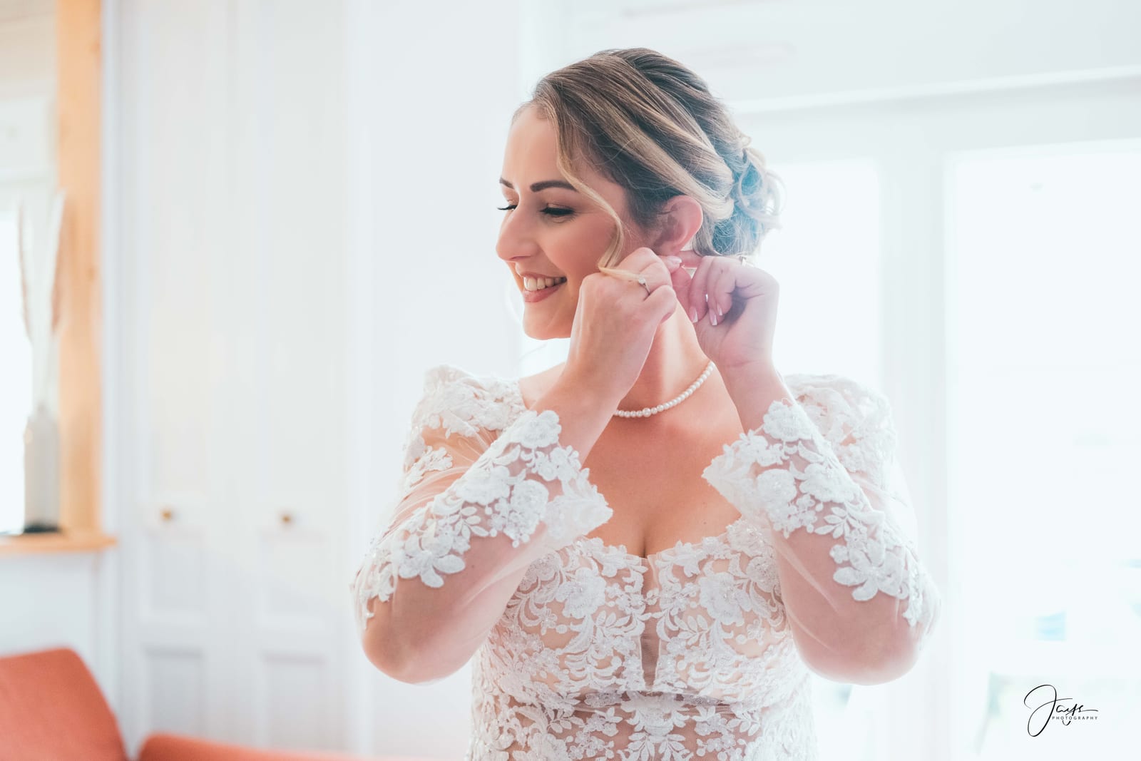 Faustine en robe de dentelle, sourire, boucles d'oreilles en perles, préparatifs de la mariée, mariage au Ferme de Maubuisson, par Jean-Baptiste Argyre (Jaysphotography)