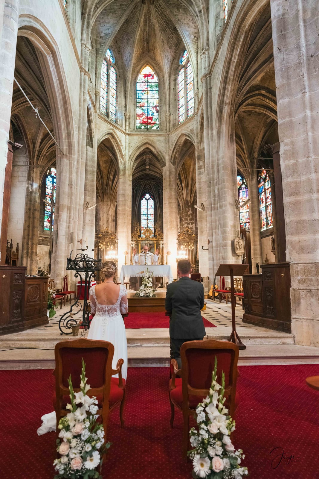Portrait du couple dans le choeur de l'église, autel et croix en fond, mariage au Ferme de Maubuisson, par Jean-Baptiste Argyre (Jaysphotography)