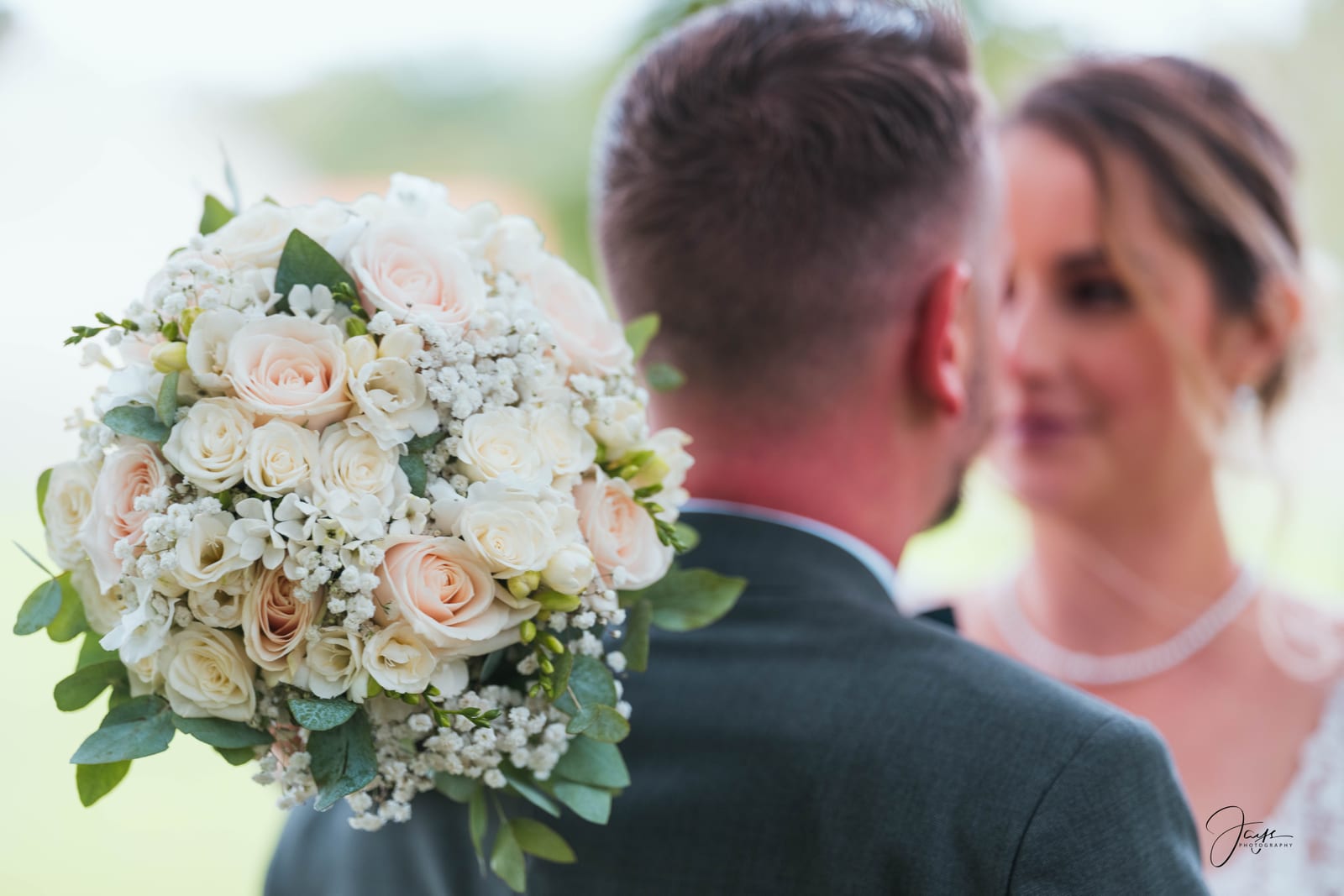 Faustine et Corentin face à face, bouquet entre eux, végétation verte en fond, mariage au Ferme de Maubuisson, par Jean-Baptiste Argyre (Jaysphotography)