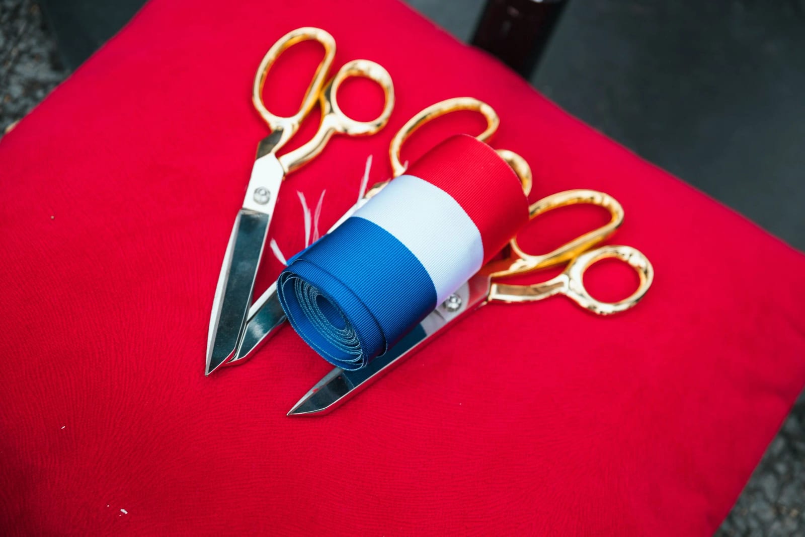 Le ruban tricolore et les ciseaux dorés posés sur un coussin rouge avant l'inauguration de la halle de Breuil-le-Vert, mariage au Breuil-le-Vert (Oise), par Jean-Baptiste Argyre (Jaysphotography)