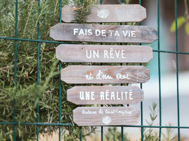 Pancartes en bois avec la citation de Saint-Exupéry, fais de ta vie un rêve, dans le jardin du domaine
