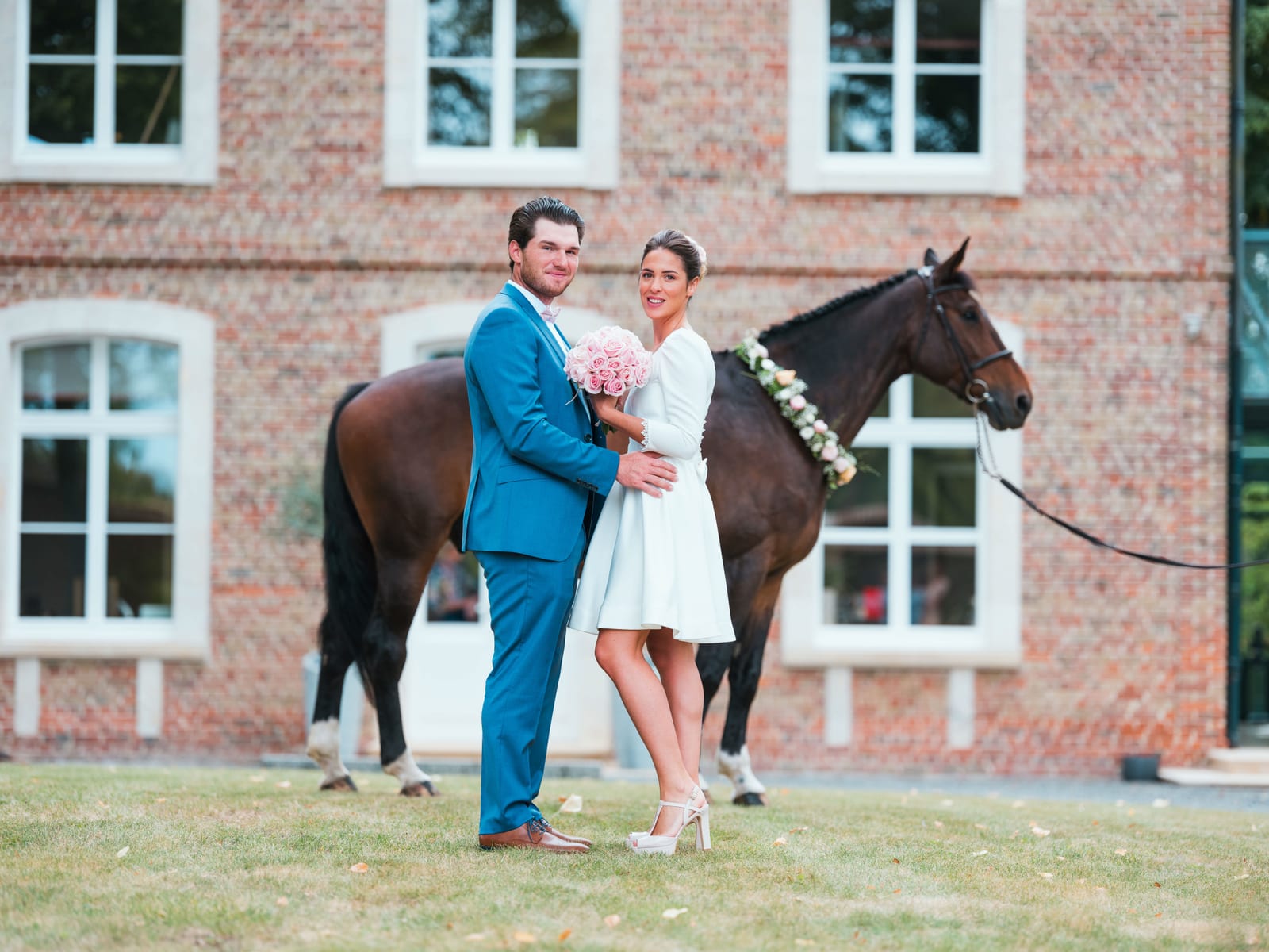 Le couple enlacé devant le château avec un cheval brun au premier plan, parc du Château de Flixecourt, mariage au Château de Flixecourt, par Jean-Baptiste Argyre (Jaysphotography)
