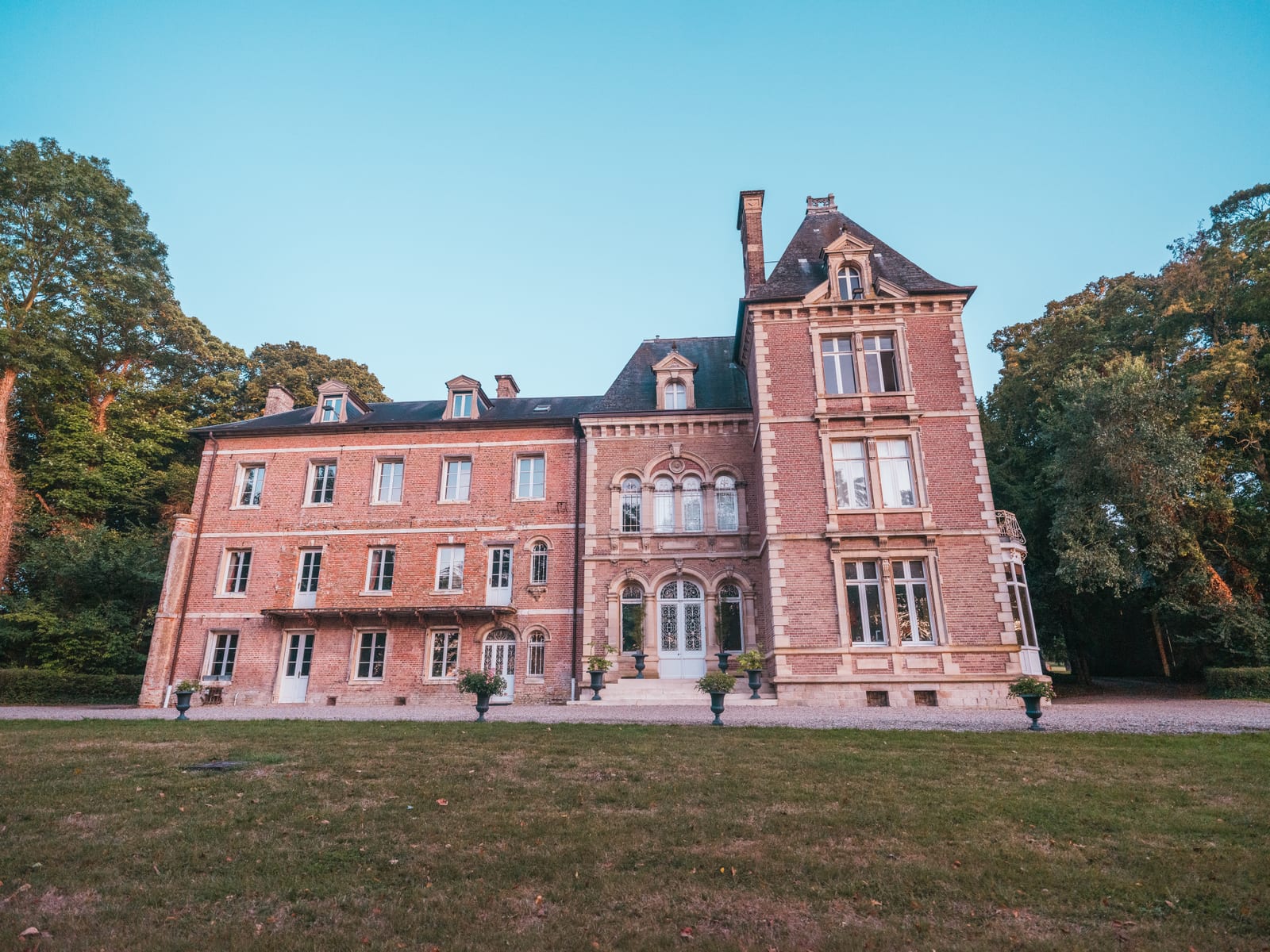 Vue de la façade principale du Château de Flixecourt en brique rouge, arbres aux premières couleurs d'automne, mariage au Château de Flixecourt, par Jean-Baptiste Argyre (Jaysphotography)