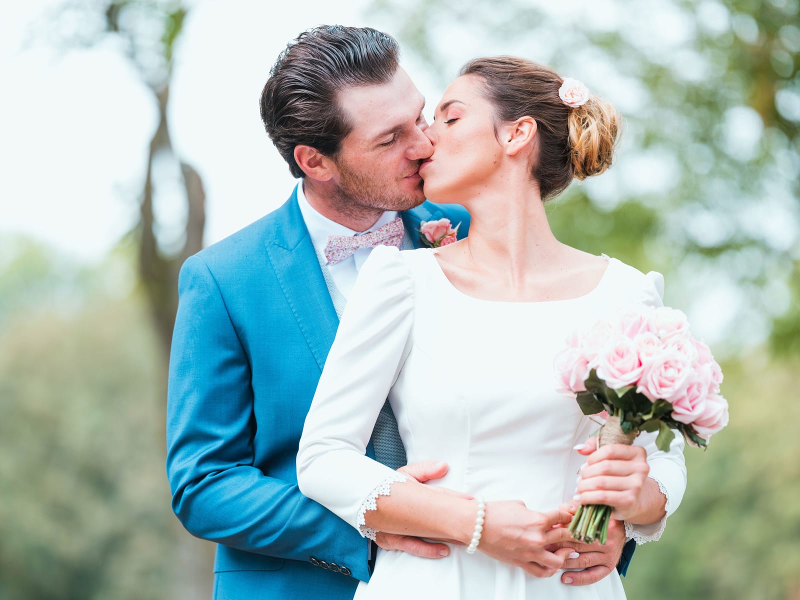 Baiser du couple en extérieur, mariée tenant son bouquet de roses roses, vert du parc en fond, mariage au Château de Flixecourt, par Jean-Baptiste Argyre (Jaysphotography)
