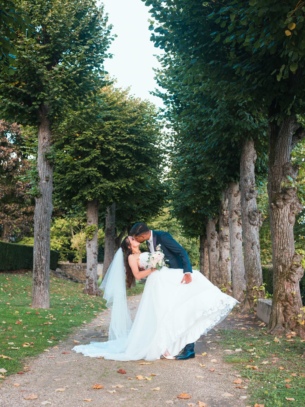 Justine et Kamielton marchant dans l'allée d'arbres du Clos Barisseuse, robe qui virevolte, mariage au Le Clos Barisseuse, par Jean-Baptiste Argyre (Jaysphotography)