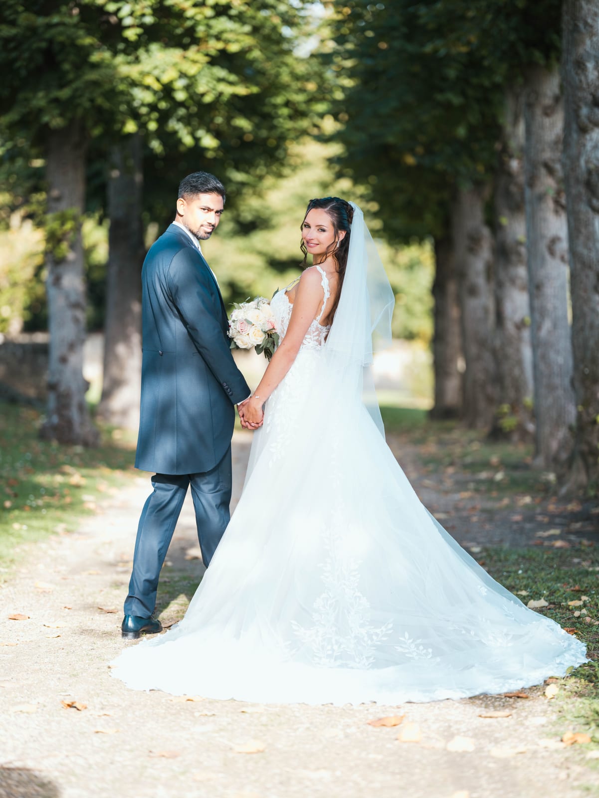 Portrait du couple marchant dans l'allée du domaine, Kamielton en costume bleu marine, mariage au Le Clos Barisseuse, par Jean-Baptiste Argyre (Jaysphotography)