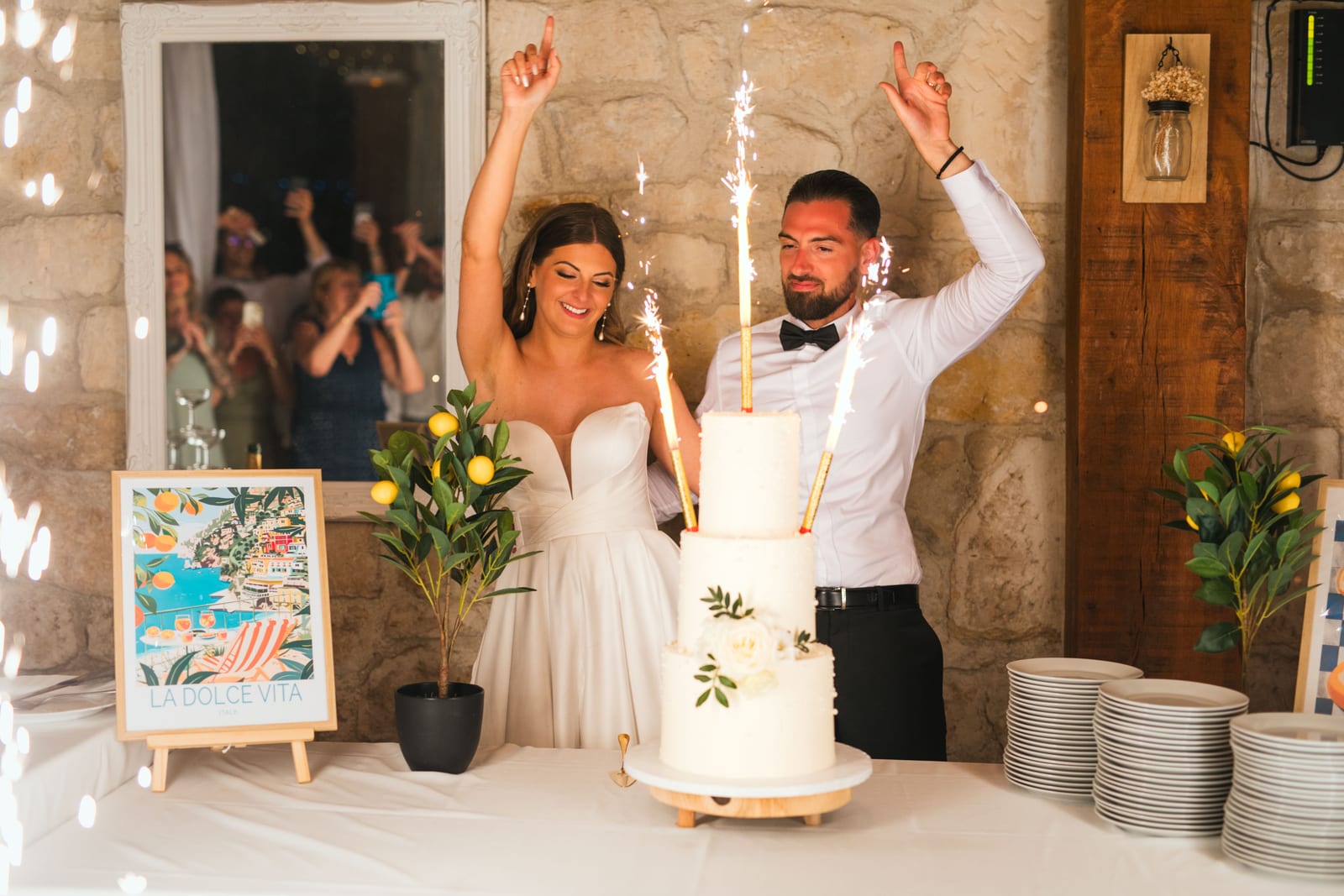 Killian et Élodie bras levés devant le gâteau et les cierges magiques, soirée de mariage au Domaine de l'Orangerie, mariage au Domaine de l'Orangerie, par Jean-Baptiste Argyre (Jaysphotography)