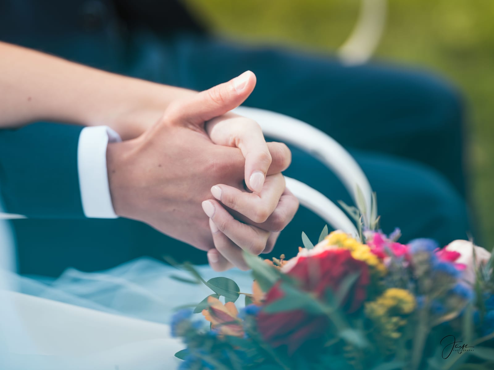 Gros plan des mains des mariés avec alliances et fleurs, détail émouvant du mariage Lara et Quentin, mariage au Château de la Houssoye, par Jean-Baptiste Argyre (Jaysphotography)