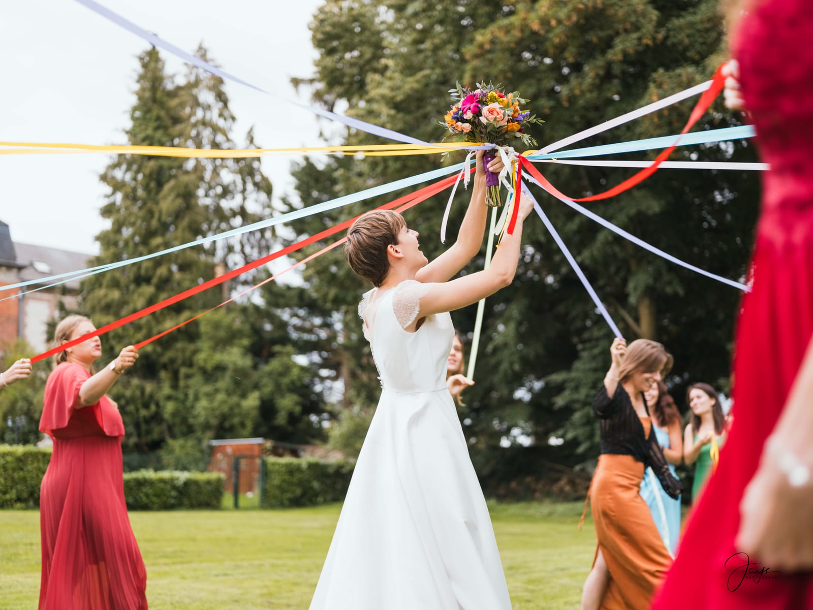 Lara et Quentin entourés de leurs proches dans les jardins du Château de la Houssoye, rubans colorés et fête en plein air, Oise, mariage au Château de la Houssoye, par Jean-Baptiste Argyre (Jaysphotography)