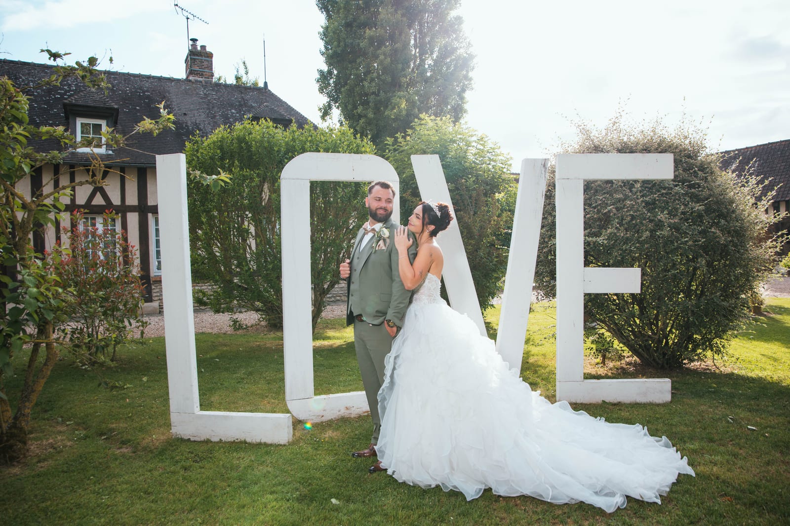 Laura et Sébastien devant les lettres géantes LOVE dans le parc, Domaine de la Croix Sauvalle, Normandie, mariage au Domaine de la Croix Sauvalle, par Jean-Baptiste Argyre (Jaysphotography)