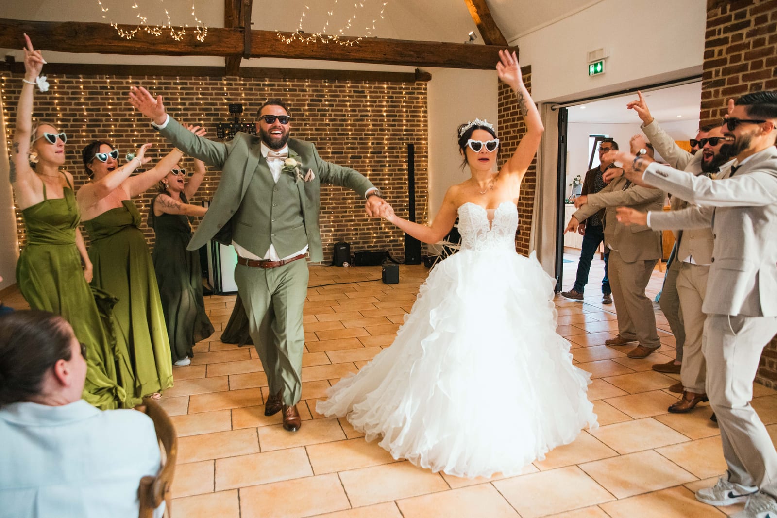 Entrée des mariés sur la piste, bras levés et lunettes en cœur, invités en haie d'honneur, Domaine de la Croix Sauvalle, mariage au Domaine de la Croix Sauvalle, par Jean-Baptiste Argyre (Jaysphotography)