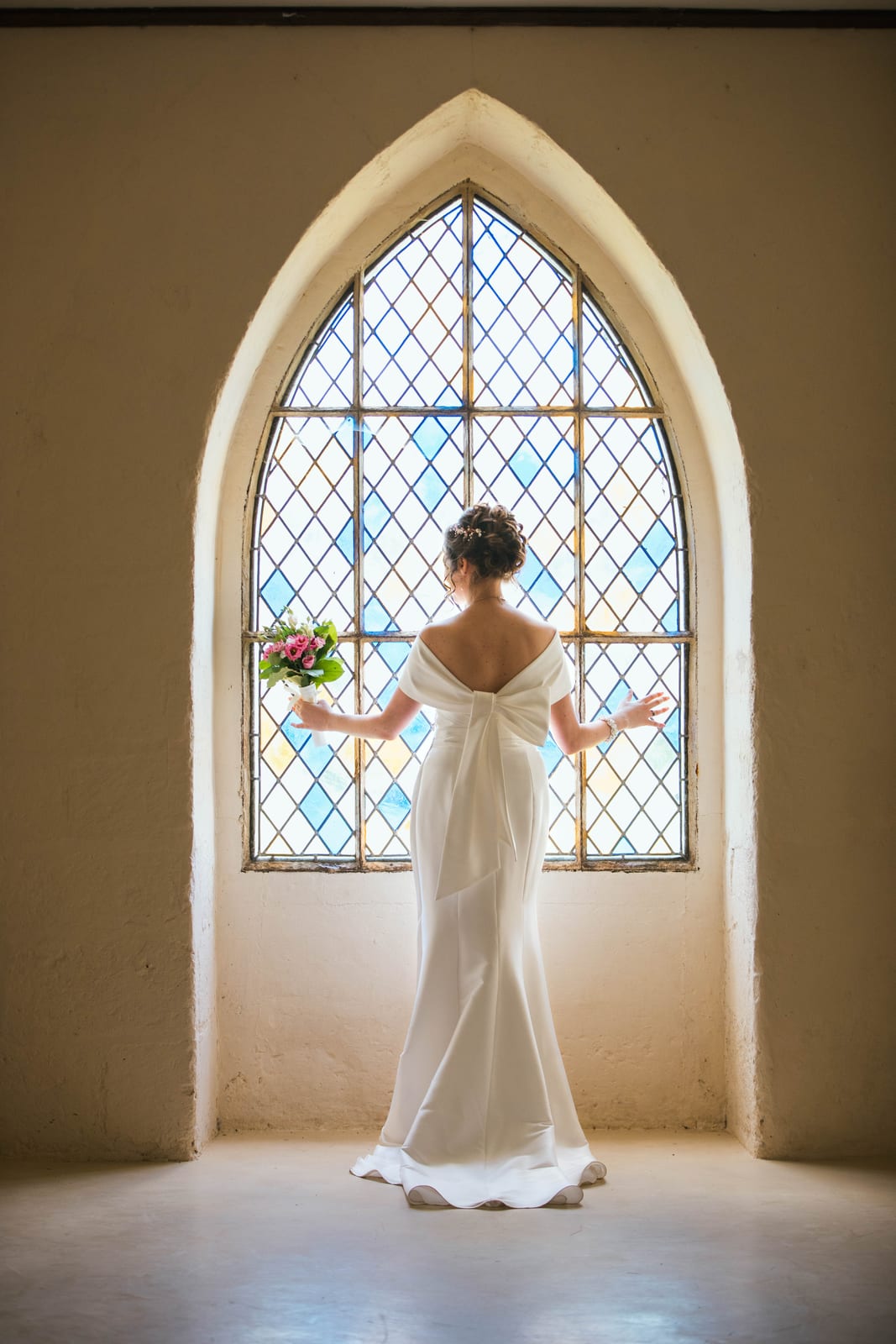 Lise seule devant la grande fenêtre gothique de l'abbaye, robe blanche en contre-jour, mariage au Abbaye Royale du Moncel, par Jean-Baptiste Argyre (Jaysphotography)