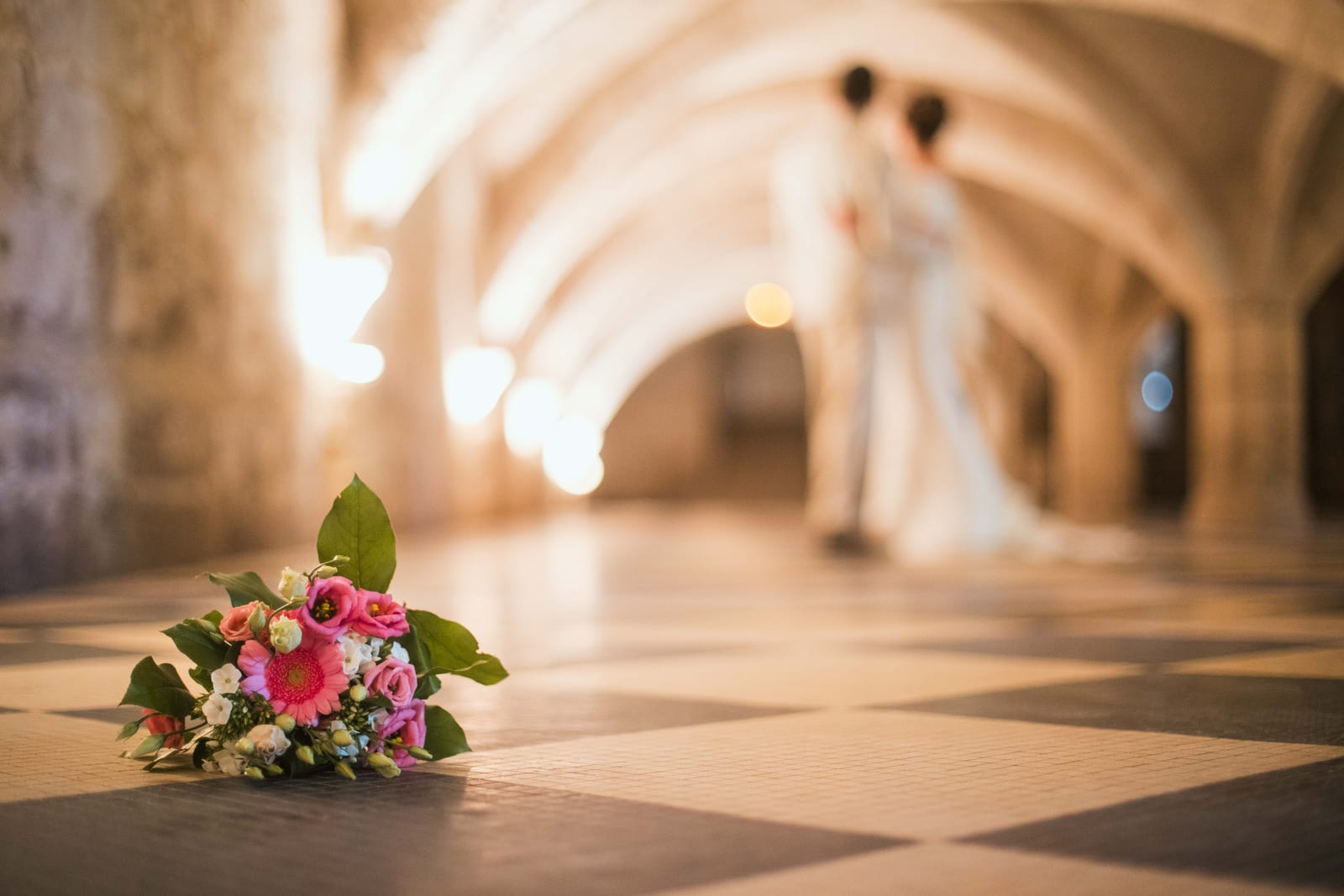 Bouquet de fleurs posé sur le carrelage, couloir voûté lumineux de l'abbaye, mariage au Abbaye Royale du Moncel, par Jean-Baptiste Argyre (Jaysphotography)