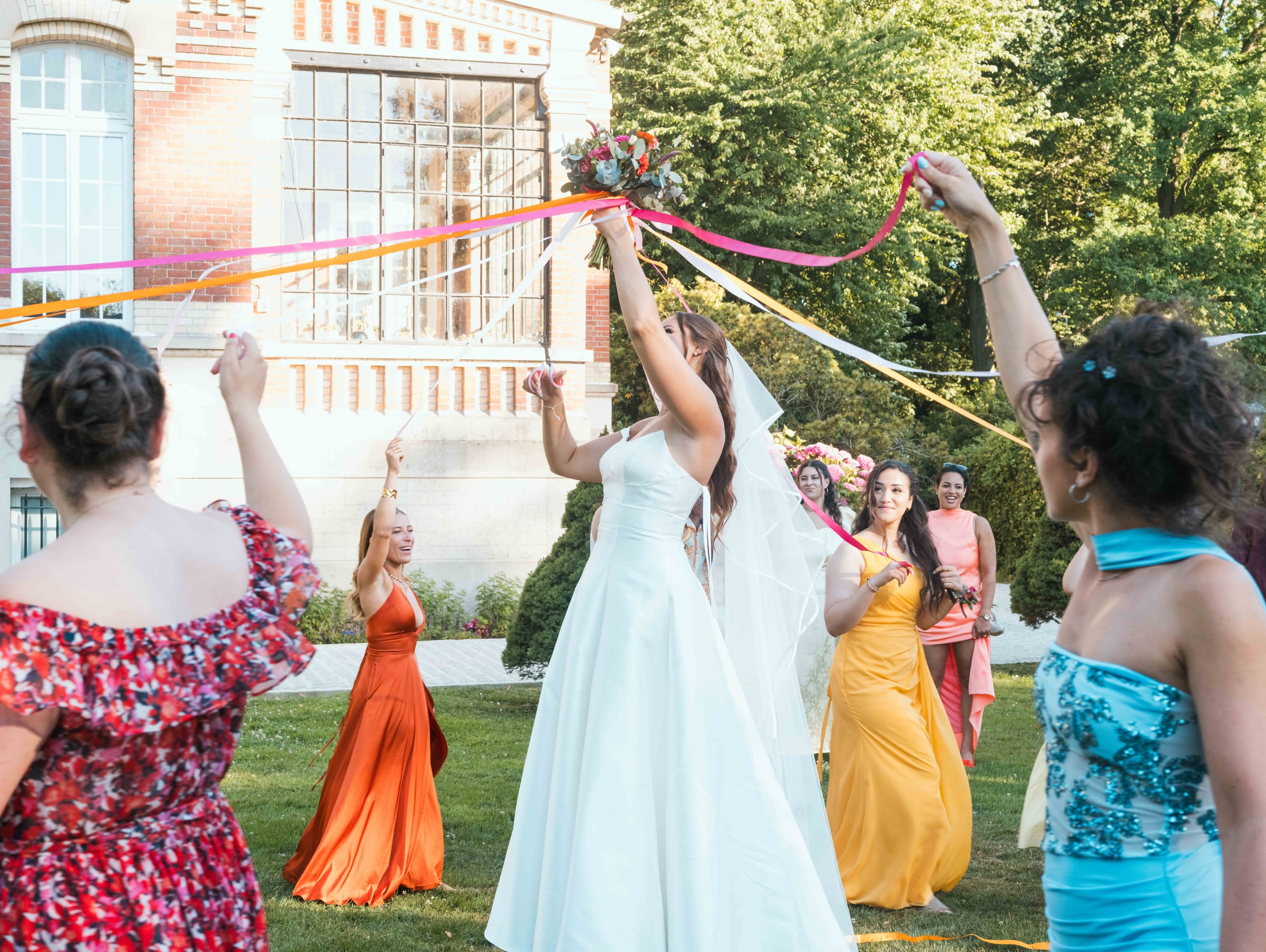 La ronde des rubans multicolores autour de Lison devant la façade du Château de Moliens, mariage au Château de Moliens, par Jean-Baptiste Argyre (Jaysphotography)