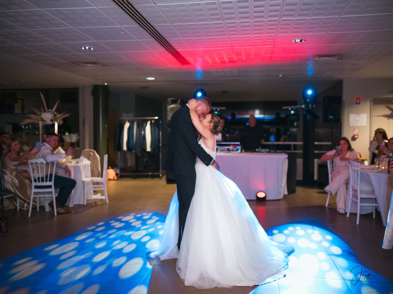 Premiere danse de Manon et Kevin dans la salle de reception, lumières colorees bleues et rouges au sol, mariage au Hippodrome de Chantilly, par Jean-Baptiste Argyre (Jaysphotography)