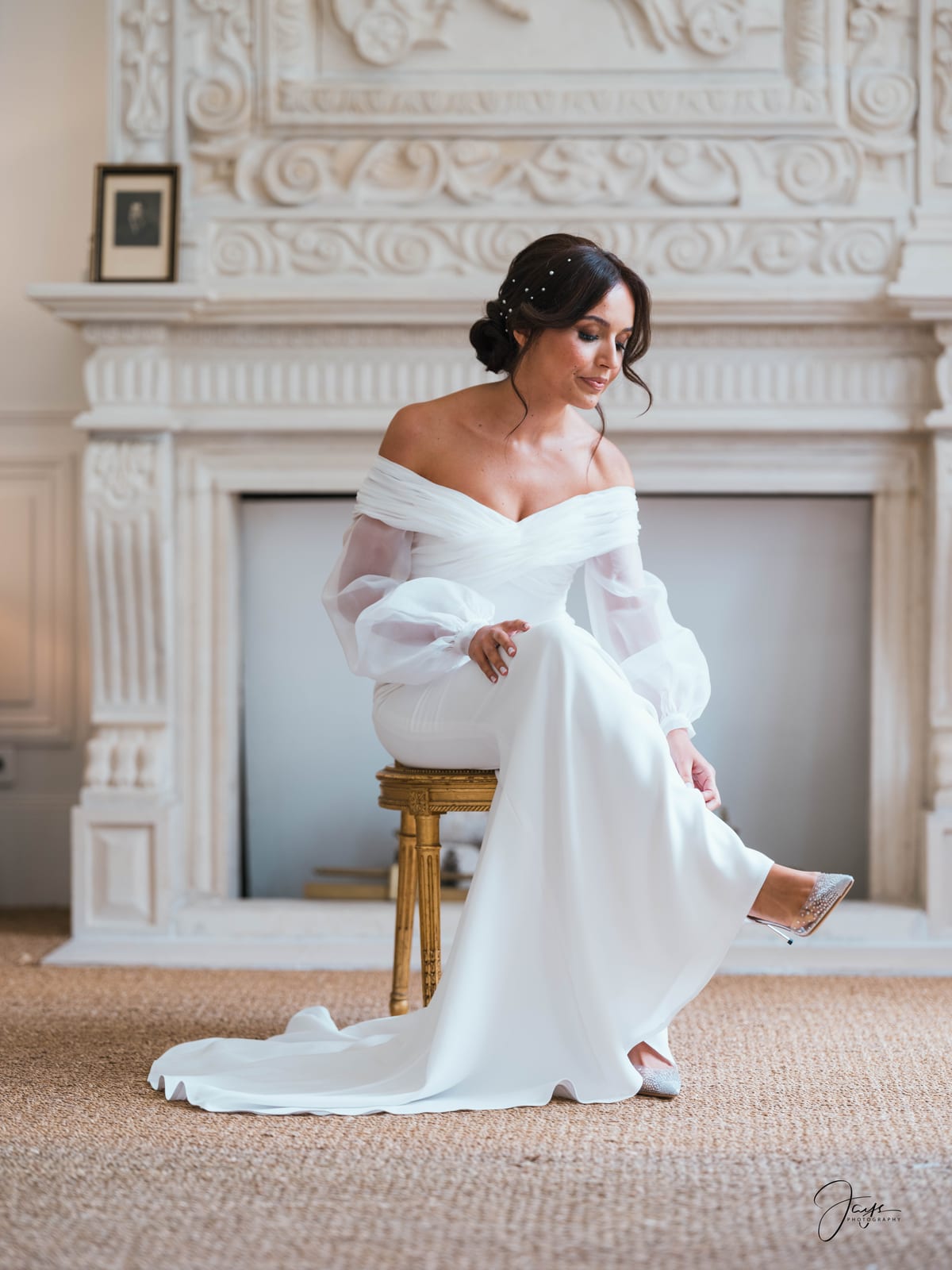 Margaux en robe de mariée blanche assise devant la cheminée en marbre, fourrure blanche sur les épaules, Château d'Auvilliers, mariage au Château d'Auvilliers, par Jean-Baptiste Argyre (Jaysphotography)