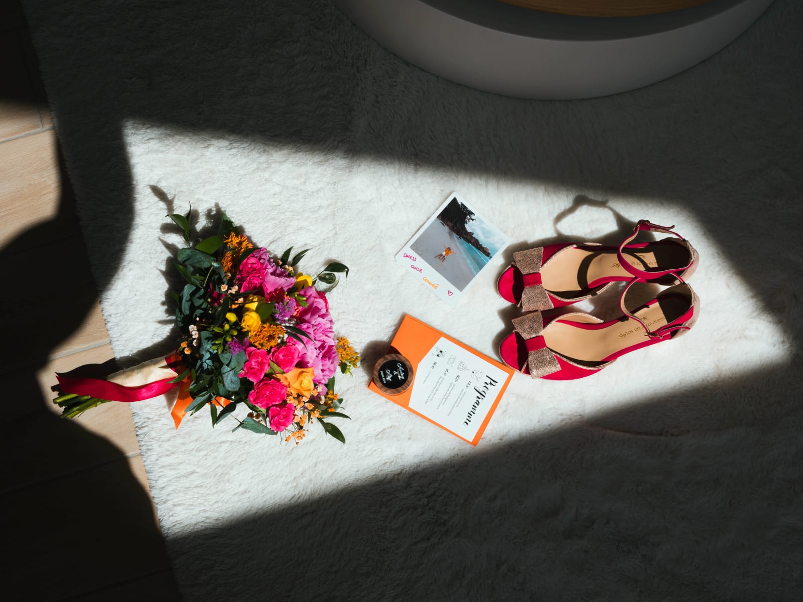 Flat lay du bouquet coloré, des escarpins roses à paillettes et du faire-part orange d'Audrey, mariage au Domaine du Bois Saint Mard, par Jean-Baptiste Argyre (Jaysphotography)
