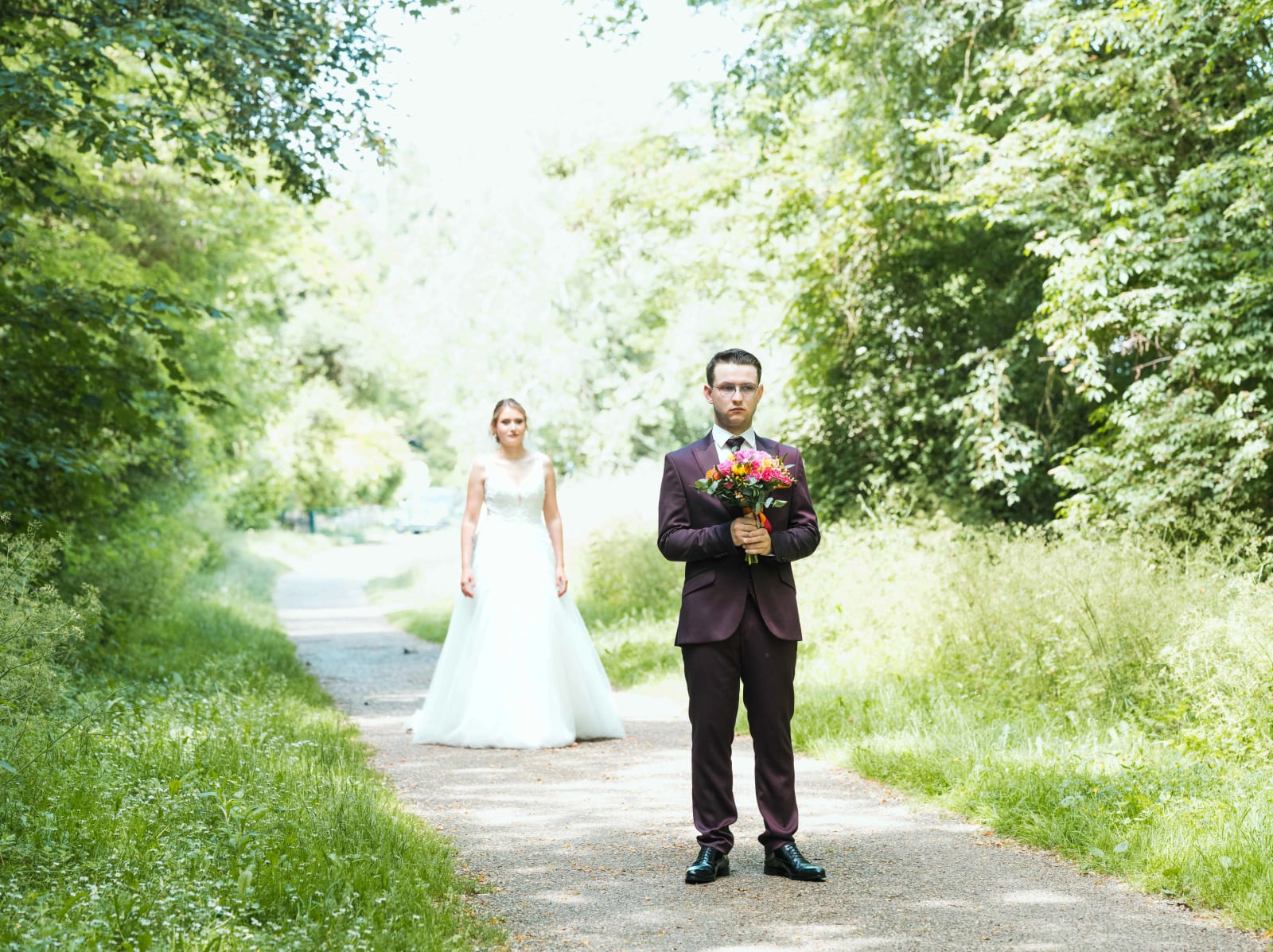 First look en forêt : Alex attend bouquet en main tandis qu'Audrey s'avance vers lui sur le chemin, mariage au Domaine du Bois Saint Mard, par Jean-Baptiste Argyre (Jaysphotography)
