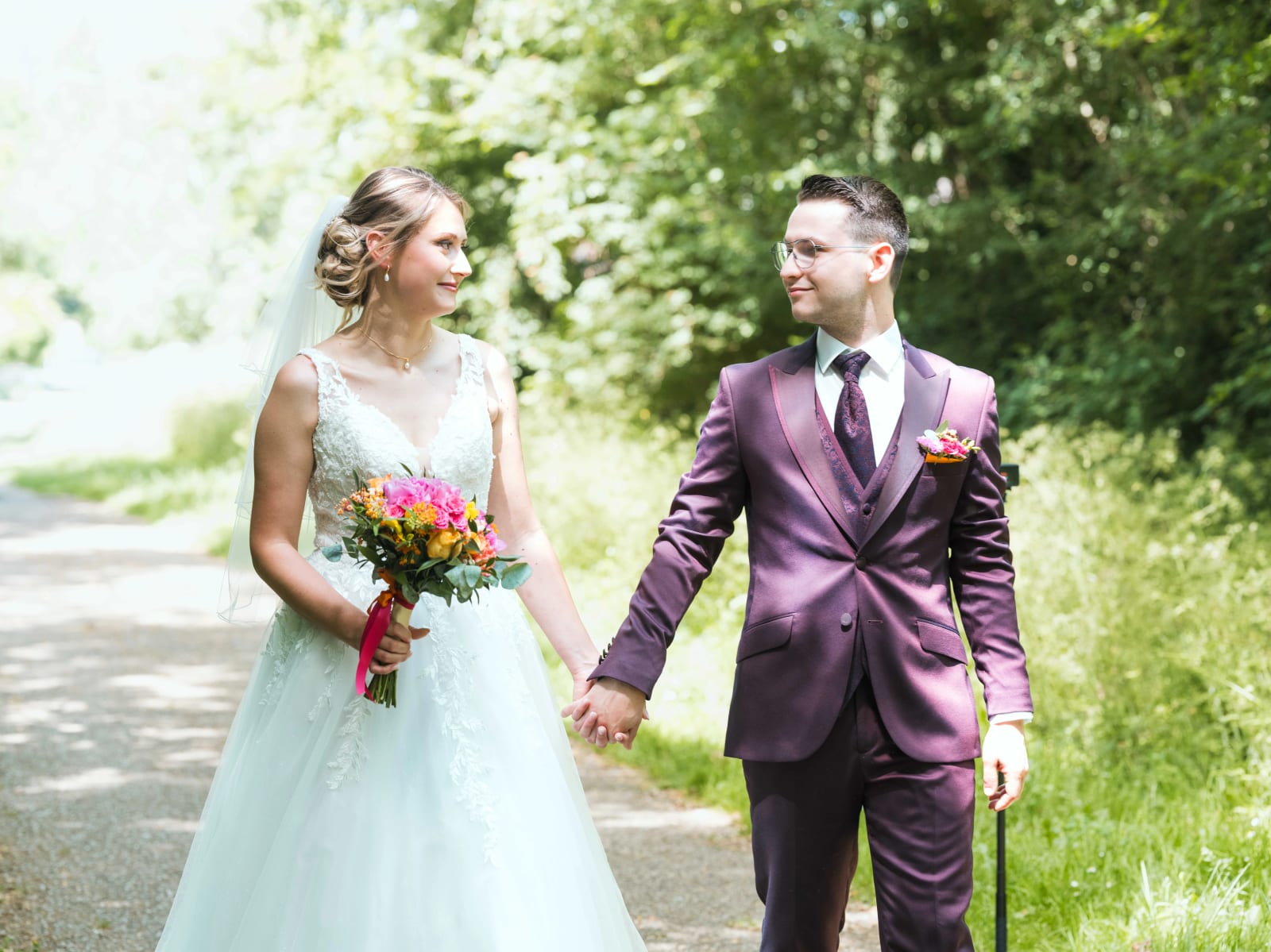 Alex et Audrey main dans la main sur un chemin forestier après le first look, bouquet coloré, mariage au Domaine du Bois Saint Mard, par Jean-Baptiste Argyre (Jaysphotography)
