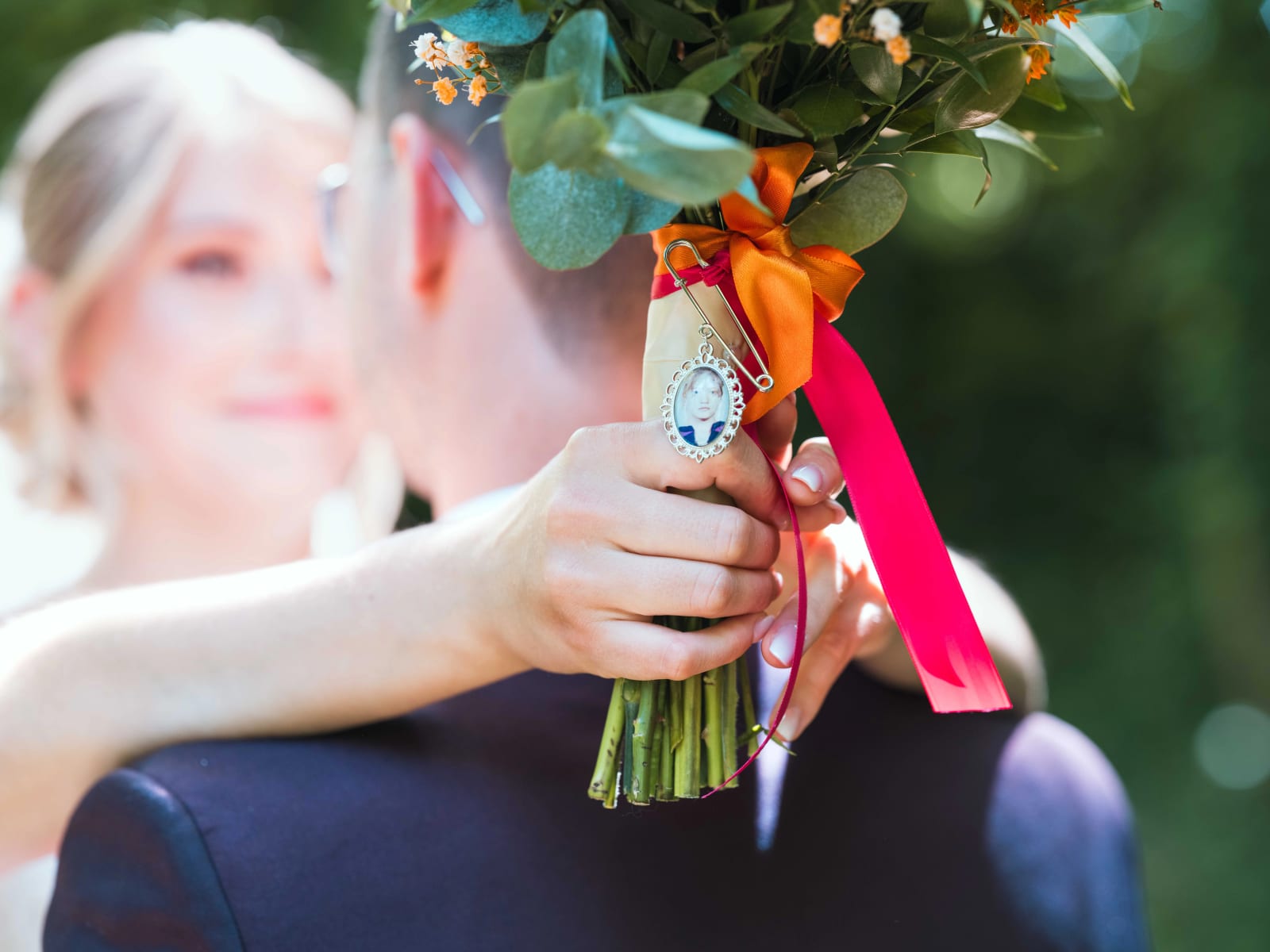 Le bouquet d'Audrey avec le pendentif photo de sa maman épinglé sur la tige, rubans orange et rose, mariage au Domaine du Bois Saint Mard, par Jean-Baptiste Argyre (Jaysphotography)