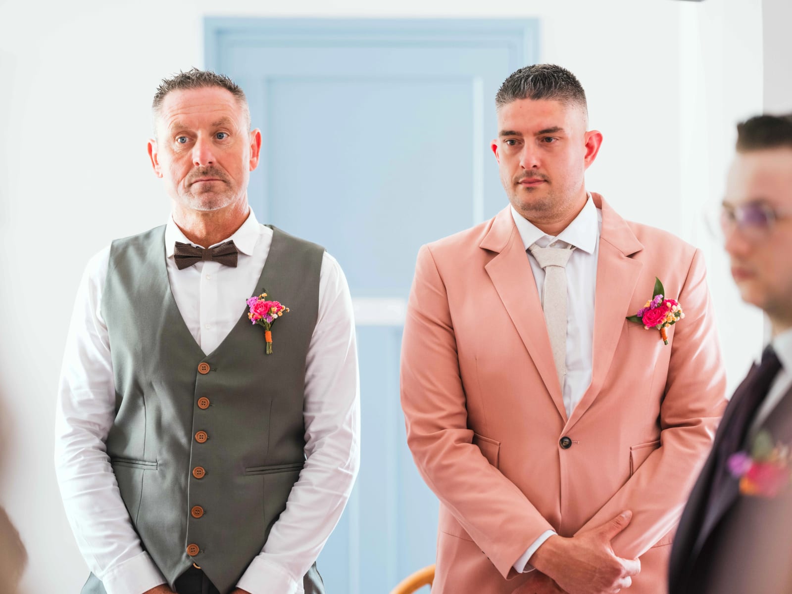Deux témoins en gilet gris et costume saumon, boutonnières fleuries, suivent la cérémonie avec émotion, mariage au Domaine du Bois Saint Mard, par Jean-Baptiste Argyre (Jaysphotography)