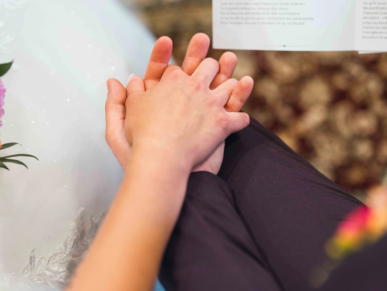 Gros plan sur les mains jointes d'Alex et Audrey pendant la cérémonie religieuse, livret de messe ouvert, mariage au Domaine du Bois Saint Mard, par Jean-Baptiste Argyre (Jaysphotography)