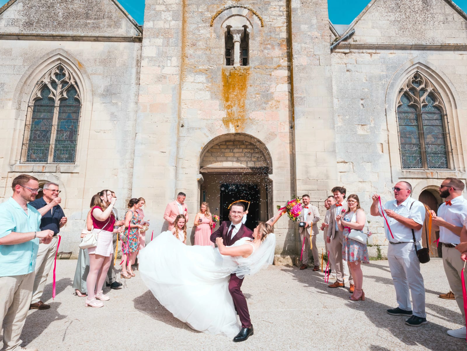 Alex soulève Audrey dans ses bras en riant à la sortie de l'église, bulles de savon dans l'air, mariage au Domaine du Bois Saint Mard, par Jean-Baptiste Argyre (Jaysphotography)