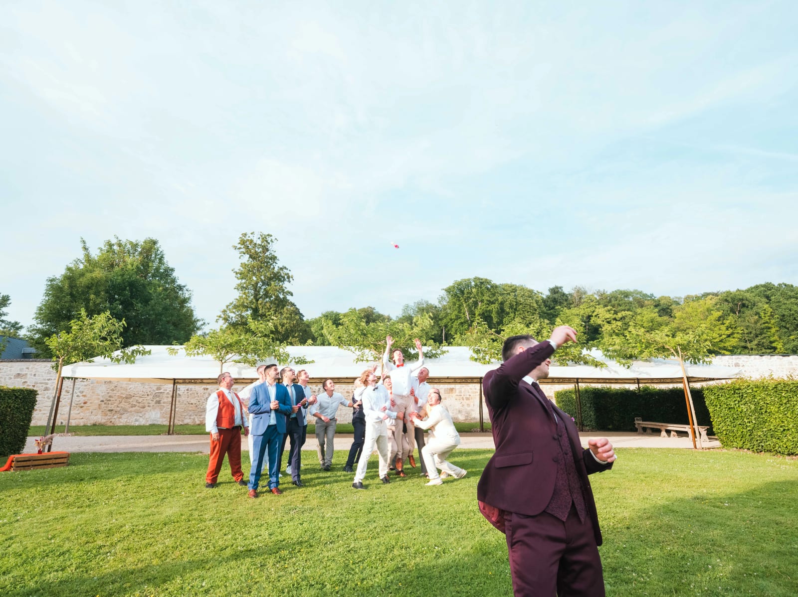 Alex lance le saucisson à la foule des invités dans le parc du domaine en fin d'après-midi, mariage au Domaine du Bois Saint Mard, par Jean-Baptiste Argyre (Jaysphotography)