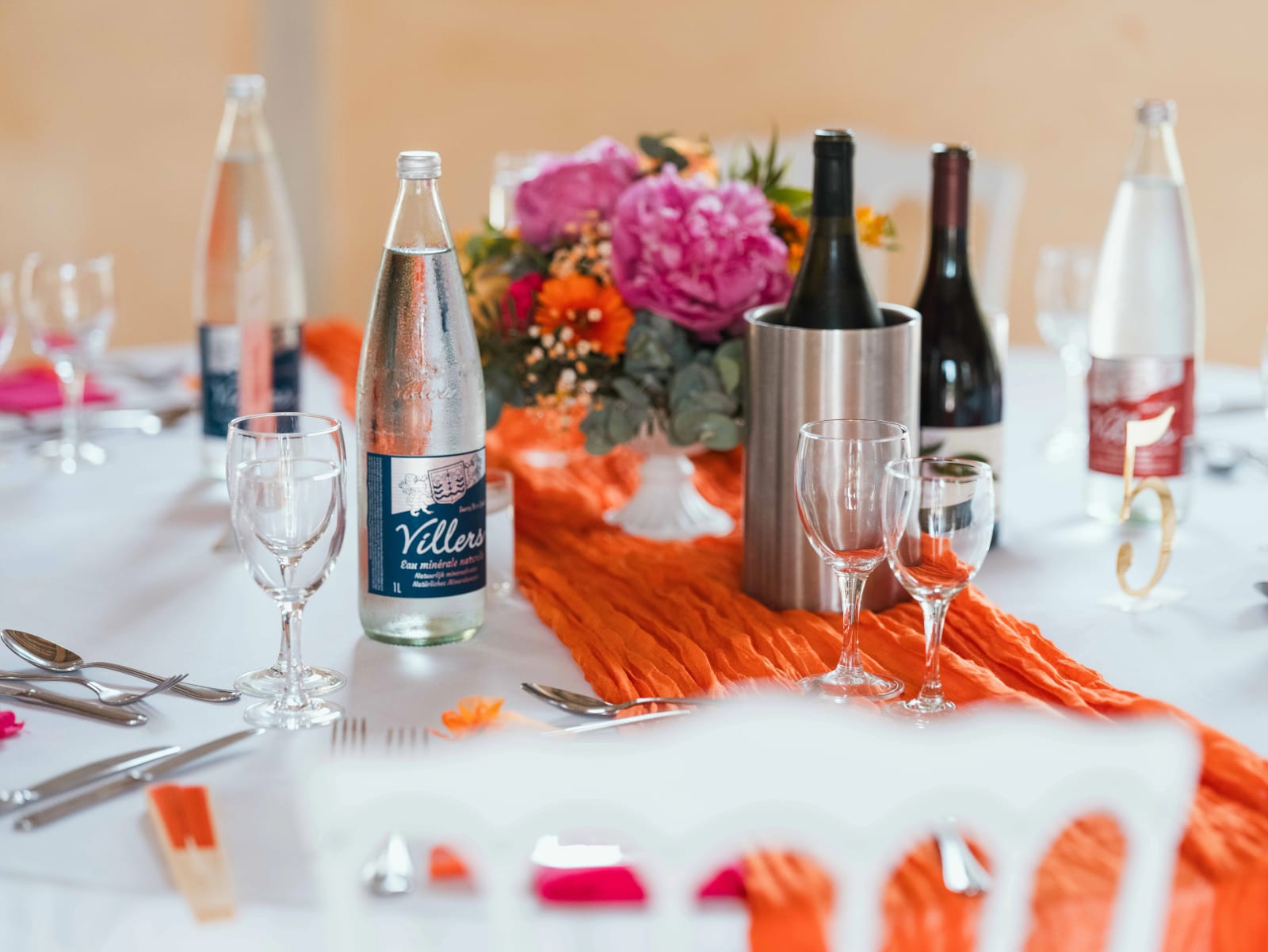 Détail d'une table dressée : chemin orange, pivoines, seau à champagne et serviettes assorties, mariage au Domaine du Bois Saint Mard, par Jean-Baptiste Argyre (Jaysphotography)