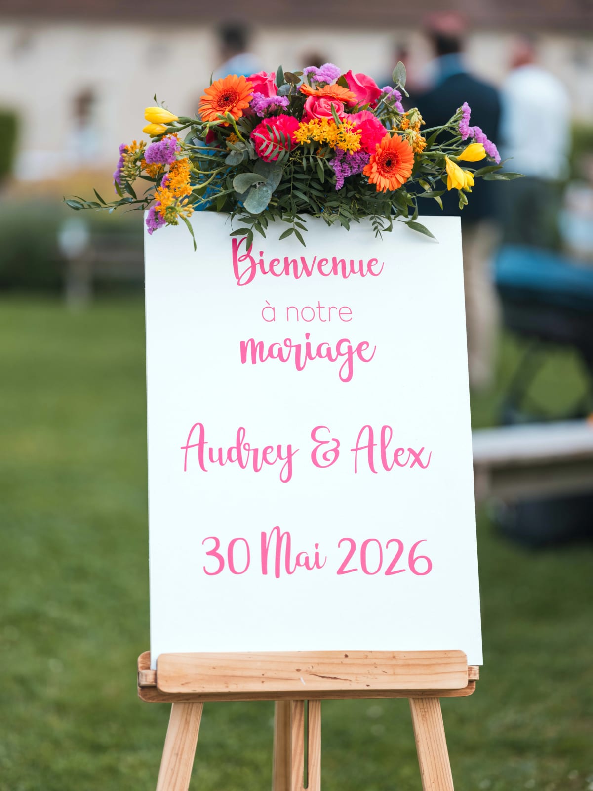Panneau de bienvenue calligraphié Audrey et Alex 30 mai 2026 sur chevalet, surmonté d'un bouquet coloré, mariage au Domaine du Bois Saint Mard, par Jean-Baptiste Argyre (Jaysphotography)