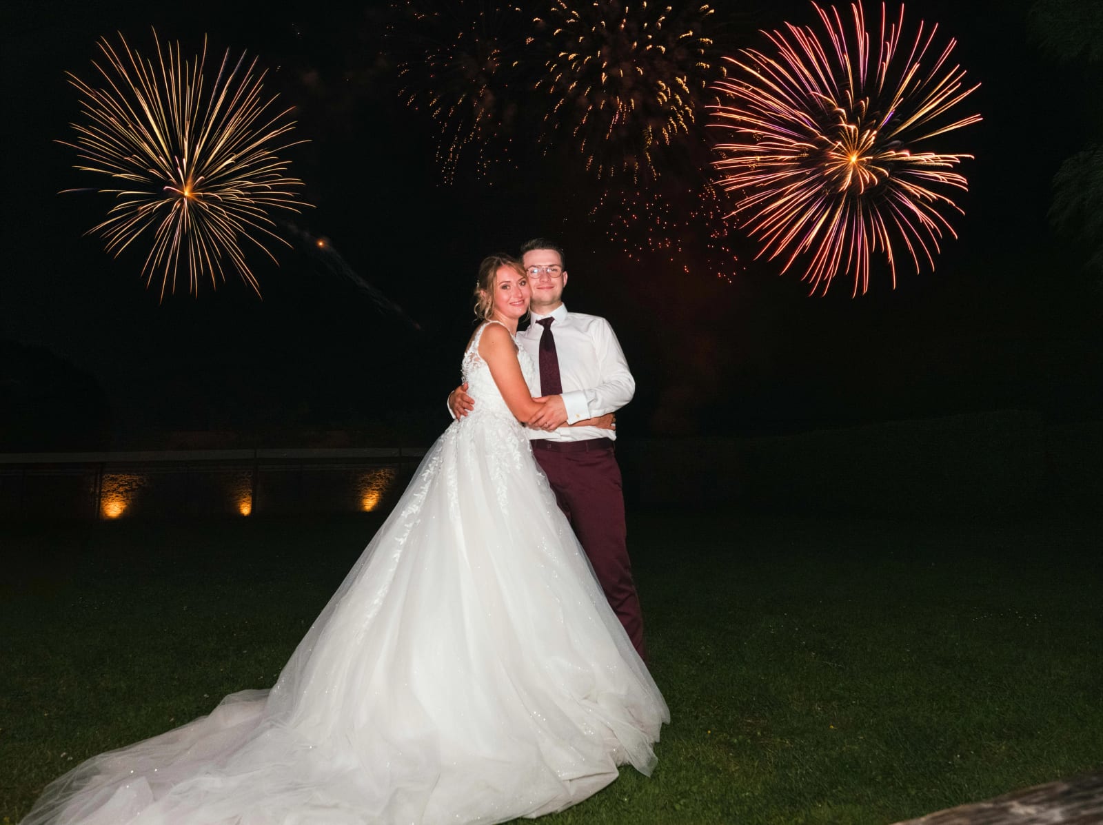 Alex et Audrey enlacés devant un feu d'artifice doré et rose dans le ciel nocturne du domaine, mariage au Domaine du Bois Saint Mard, par Jean-Baptiste Argyre (Jaysphotography)