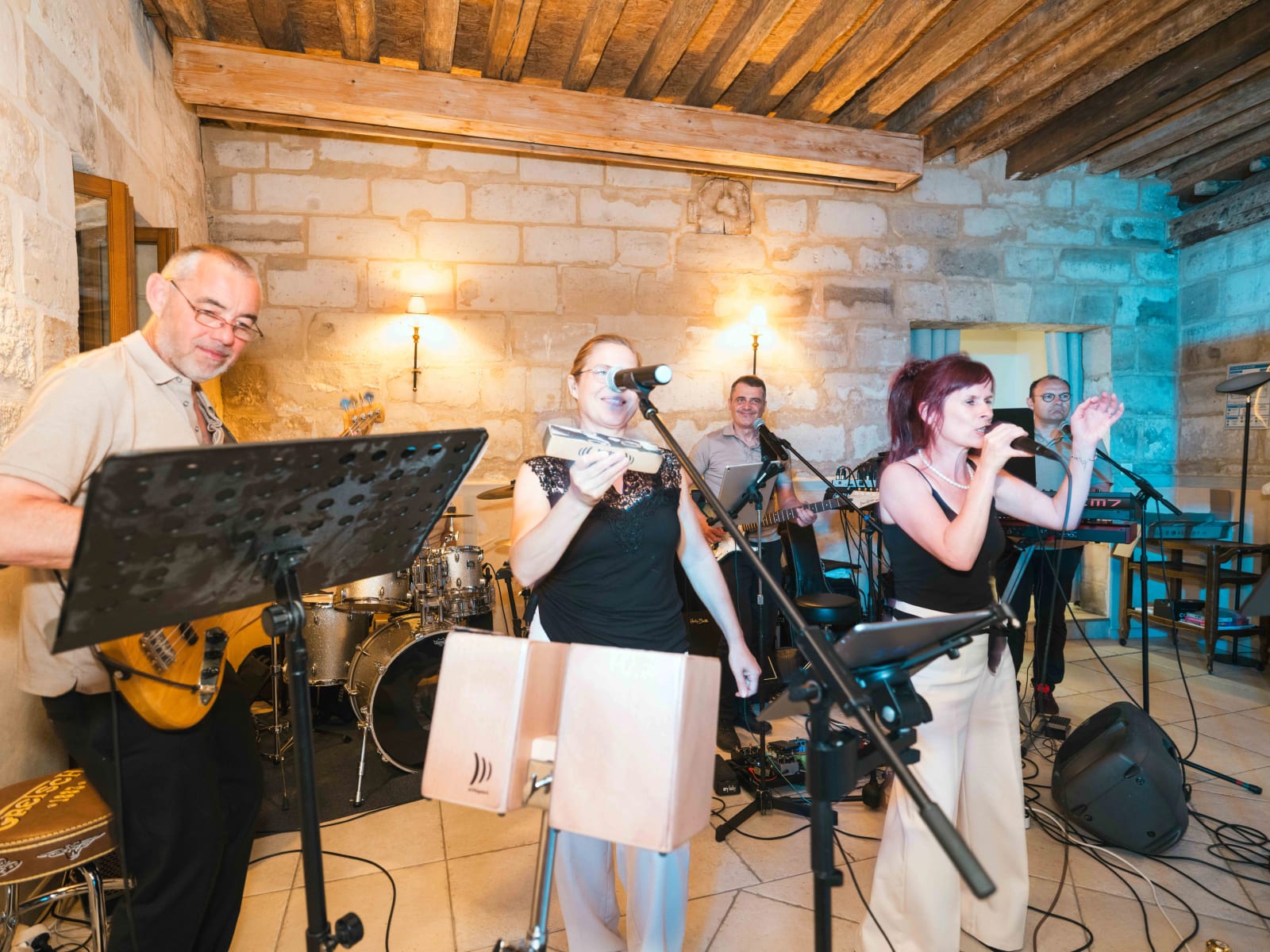 Le groupe de musiciens en live sur scène dans la salle en pierre pendant la soirée, mariage au Domaine du Bois Saint Mard, par Jean-Baptiste Argyre (Jaysphotography)