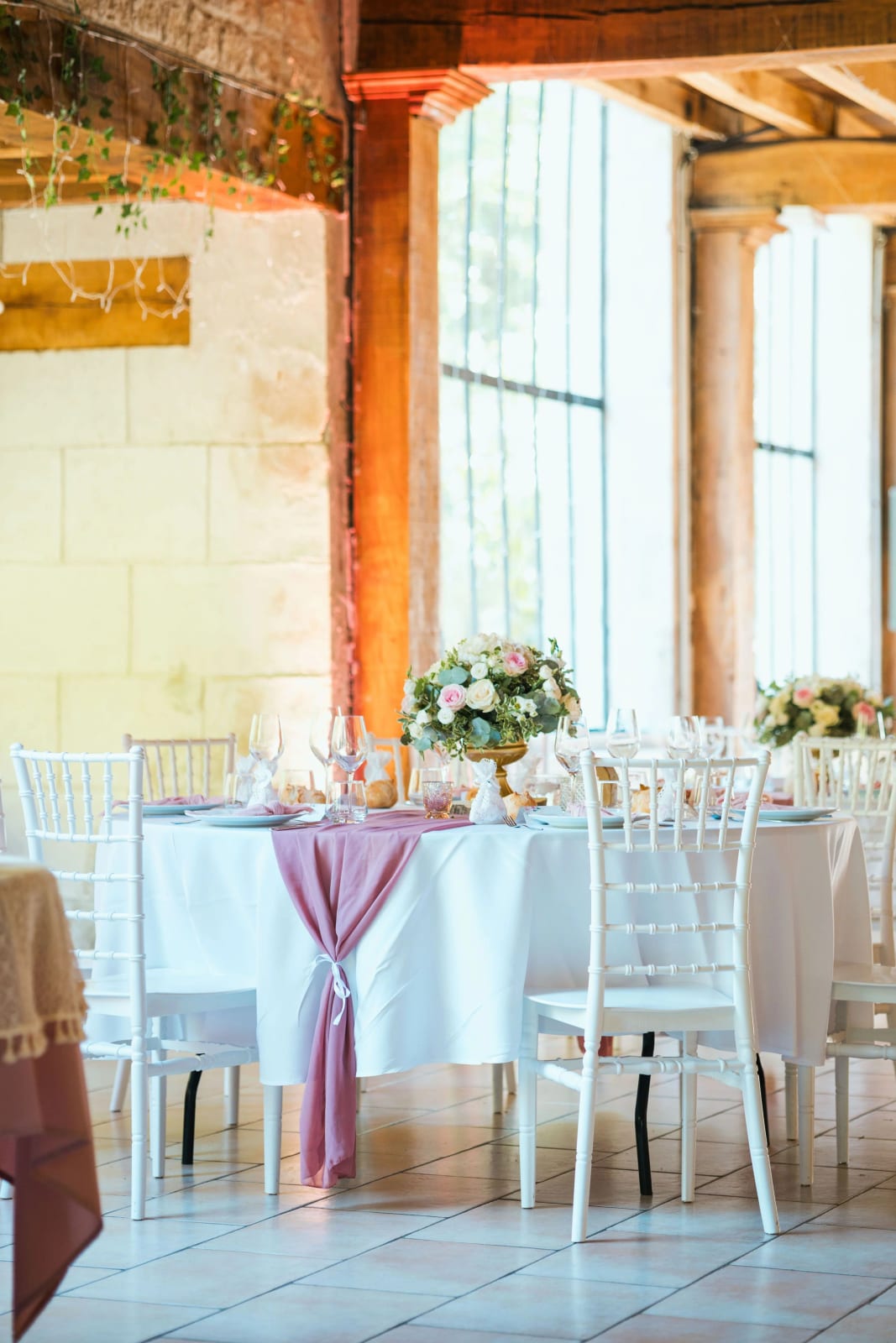 Table dressée sous les verrières de l'orangerie, chemin de table vieux rose noué et compositions de roses et pivoines sur pied doré, mariage au Domaine de l'Orangerie, par Jean-Baptiste Argyre (Jaysphotography)