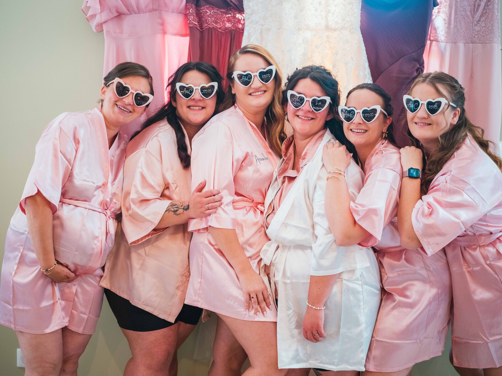 Les six demoiselles d'honneur en peignoirs de satin rose et lunettes en cœur pendant les préparatifs — mariage au Domaine du Bois Saint Mard, par Jean-Baptiste Argyre (Jaysphotography)