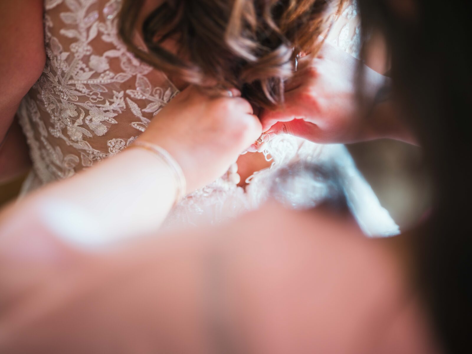 Détail du laçage du dos de la robe en dentelle pendant l'habillage de la mariée — mariage au Domaine du Bois Saint Mard, par Jean-Baptiste Argyre (Jaysphotography)
