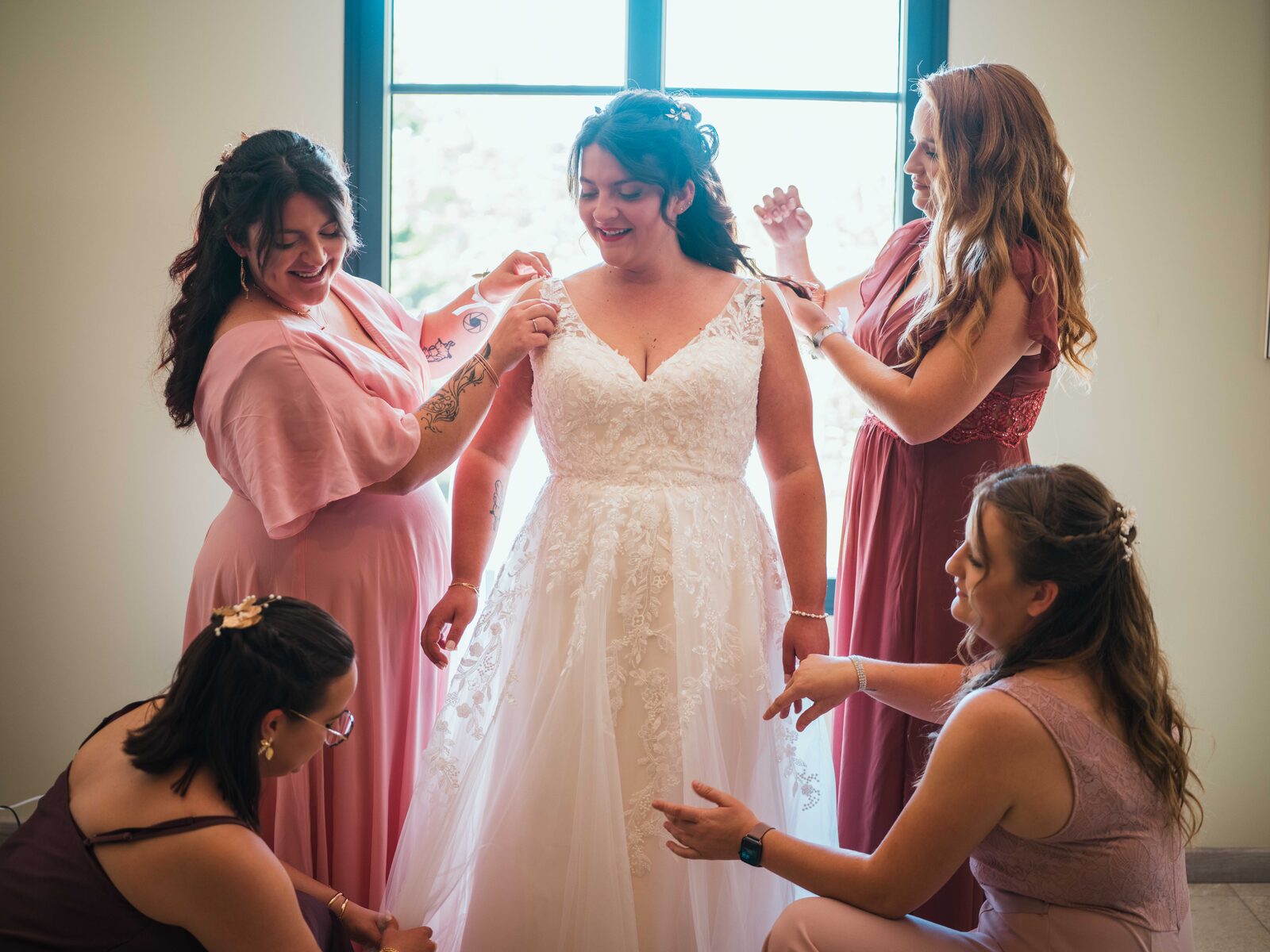 La mariée entourée de ses demoiselles d'honneur qui l'aident à enfiler sa robe — mariage au Domaine du Bois Saint Mard, par Jean-Baptiste Argyre (Jaysphotography)