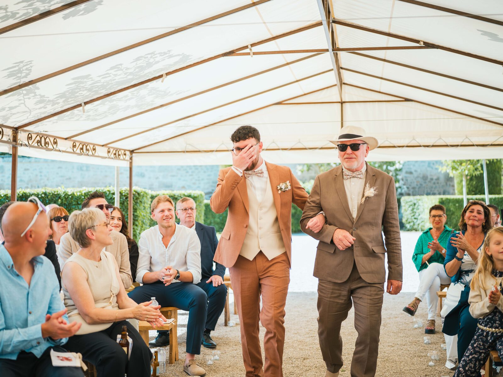 Entrée bouleversante du marié en larmes, accompagné de son père au chapeau panama, sous les applaudissements — mariage au Domaine du Bois Saint Mard, par Jean-Baptiste Argyre (Jaysphotography)