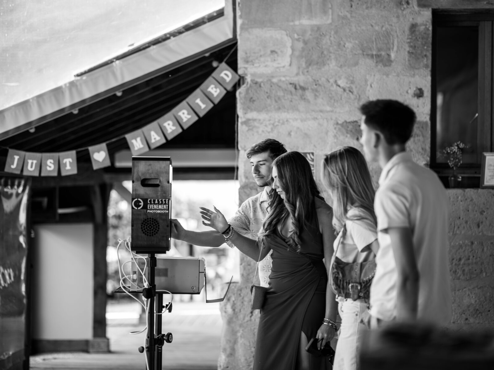 Des invités s'amusent devant la borne photo sous la banderole « Just Married », noir et blanc — mariage au Domaine du Bois Saint Mard, par Jean-Baptiste Argyre (Jaysphotography)