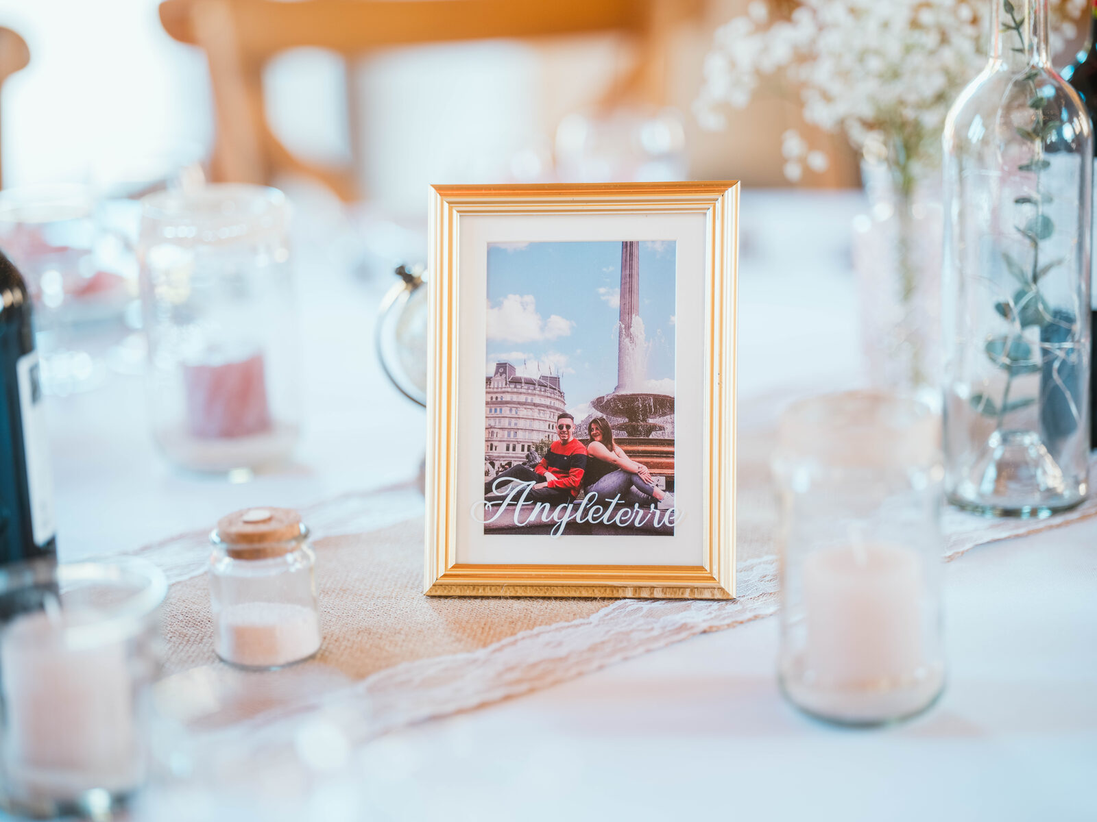 Détail de décoration de table : un cadre photo du couple sur le thème du voyage, marqué « Angleterre » — mariage au Domaine du Bois Saint Mard, par Jean-Baptiste Argyre (Jaysphotography)