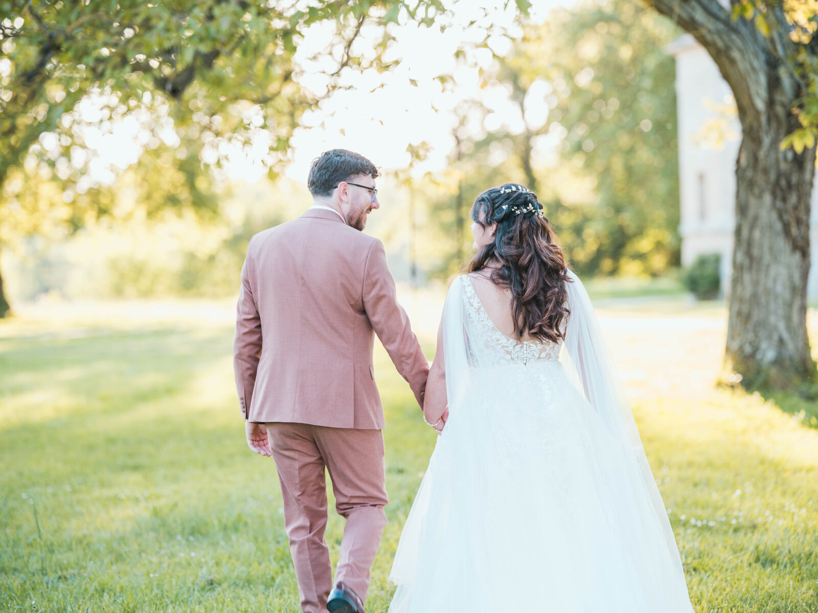 Les mariés s'éloignent main dans la main vers le château à la golden hour — mariage au Domaine du Bois Saint Mard, par Jean-Baptiste Argyre (Jaysphotography)