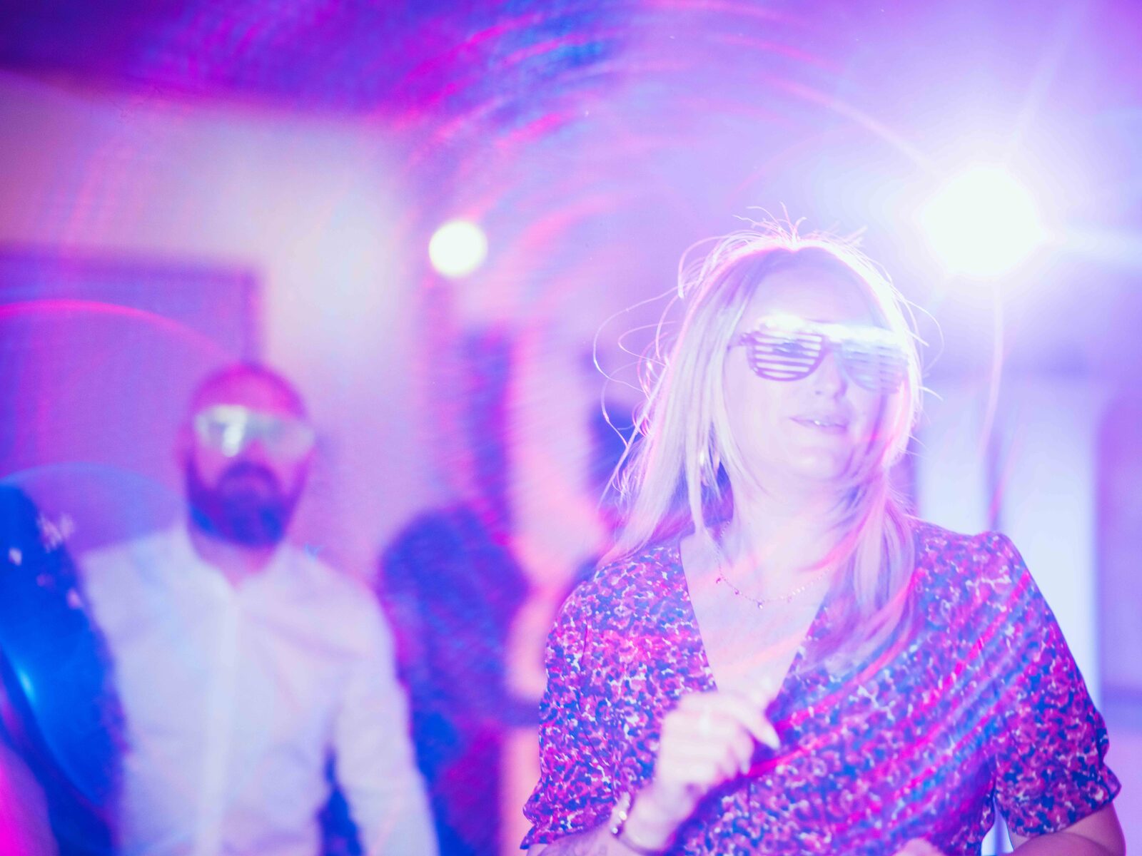 Une invitée danse, lunettes lumineuses, sous les jeux de lumière de la soirée — mariage au Domaine du Bois Saint Mard, par Jean-Baptiste Argyre (Jaysphotography)