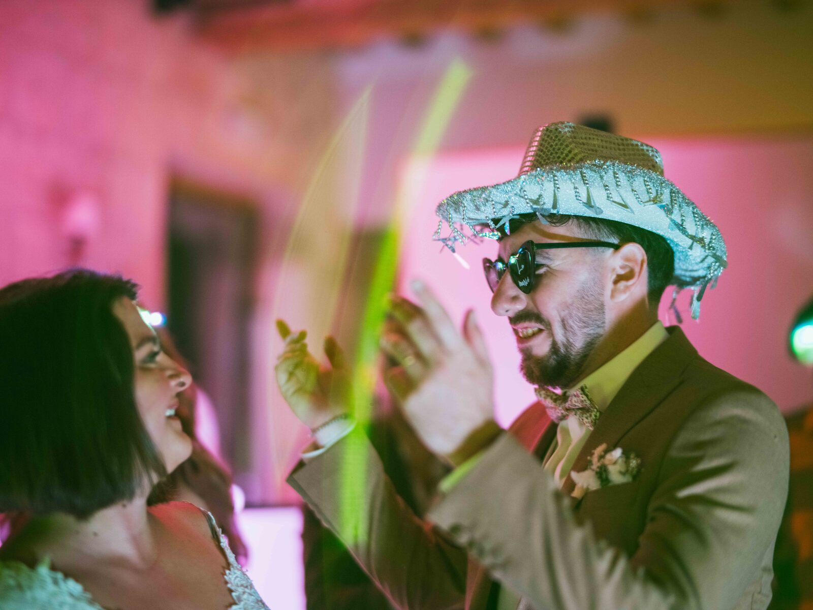 Le marié danse coiffé d'un chapeau argenté à franges aux côtés de la mariée — mariage au Domaine du Bois Saint Mard, par Jean-Baptiste Argyre (Jaysphotography)