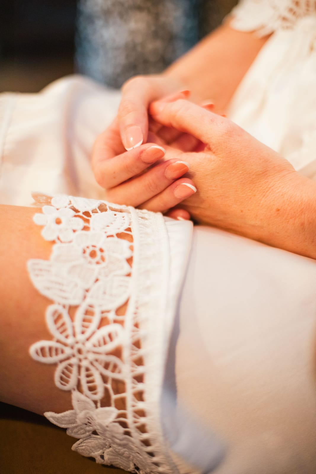 Gros plan sur les mains jointes d'Amandine posées sur sa robe de chambre en dentelle pendant les préparatifs, mariage au Domaine de Senercy, par Jean-Baptiste Argyre (Jaysphotography)